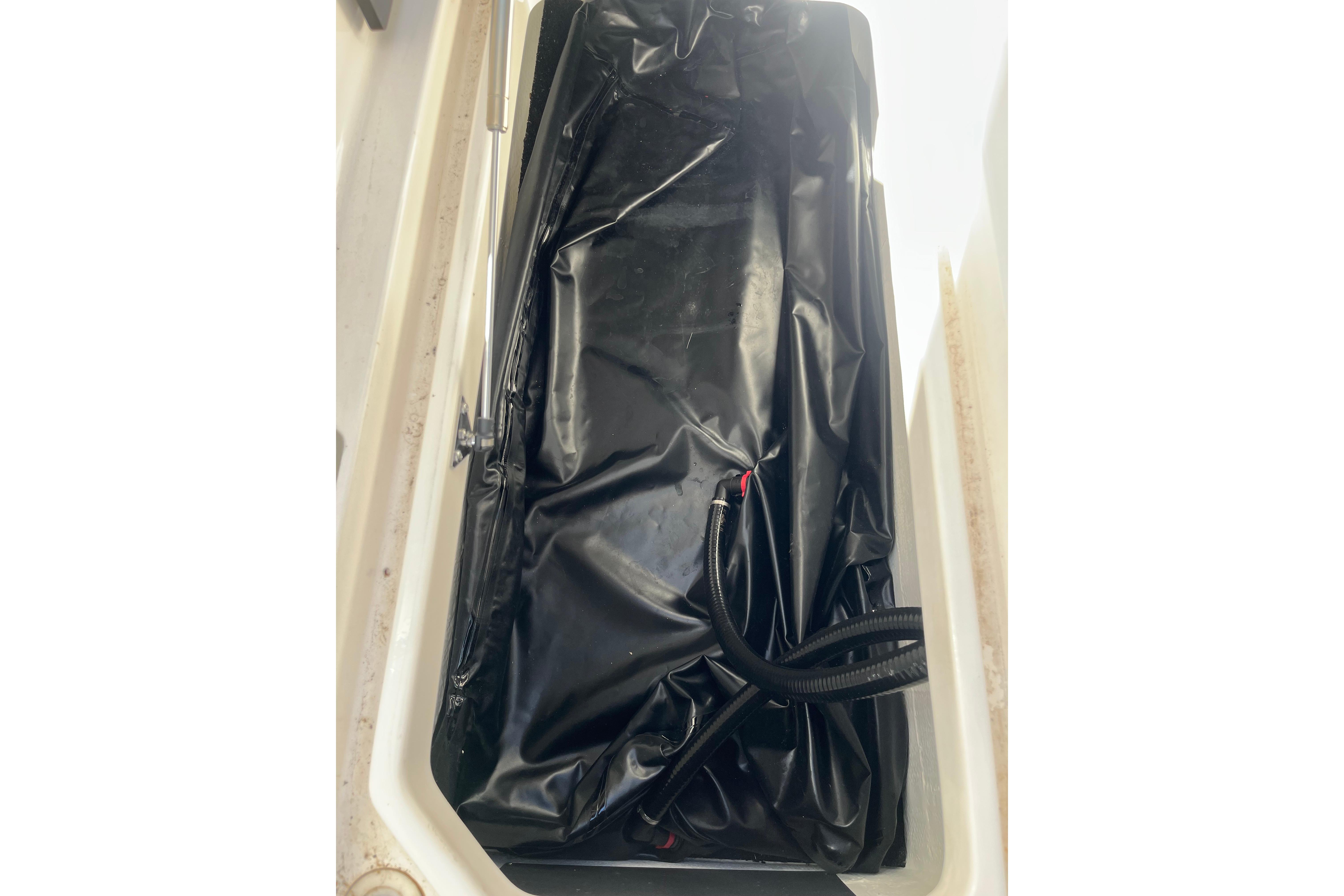 2024 Regal LS9 Surf boat storage compartment with black liner and hose.