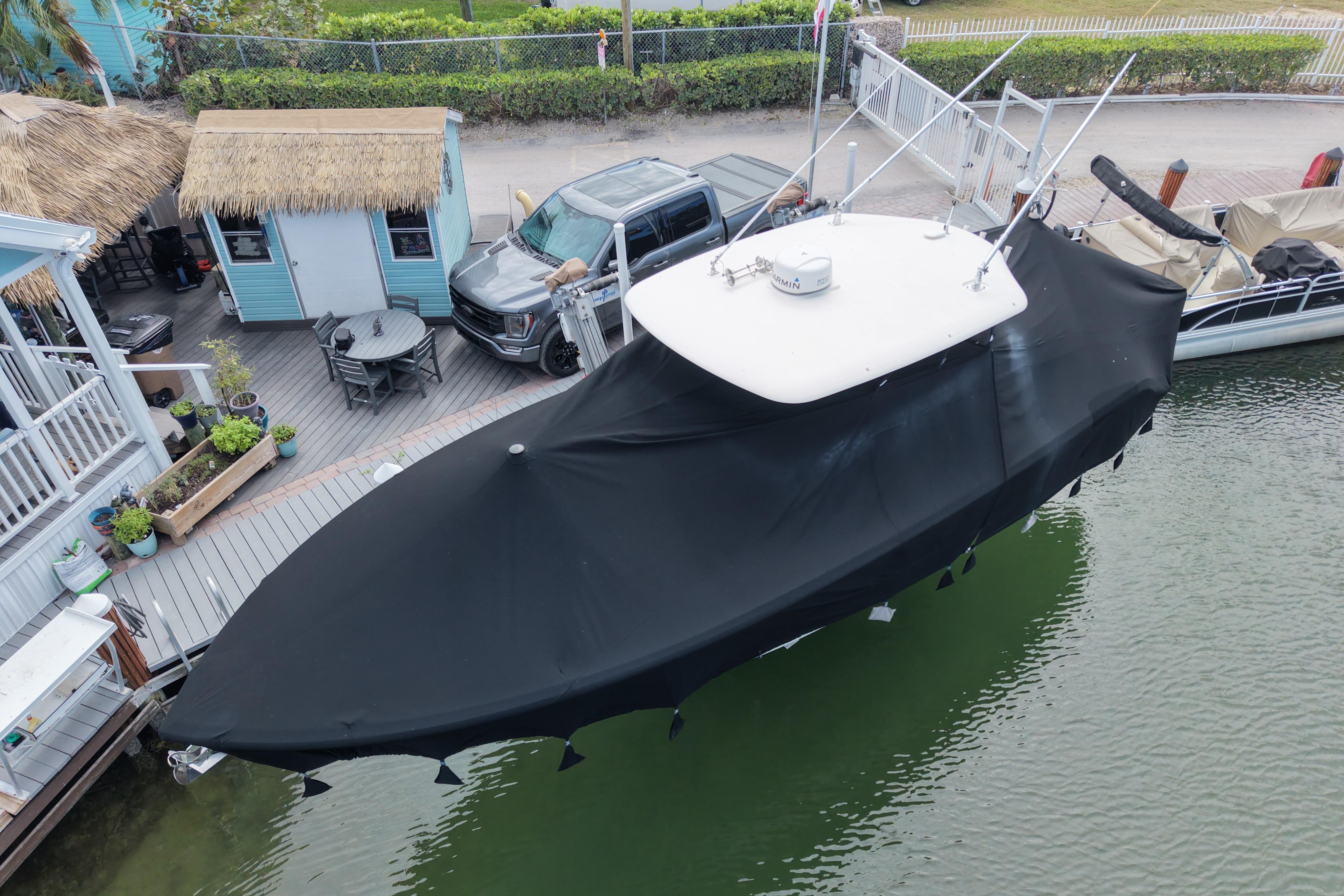 2015 Cobia 344 Center Console boat covered, docked near a waterfront deck.