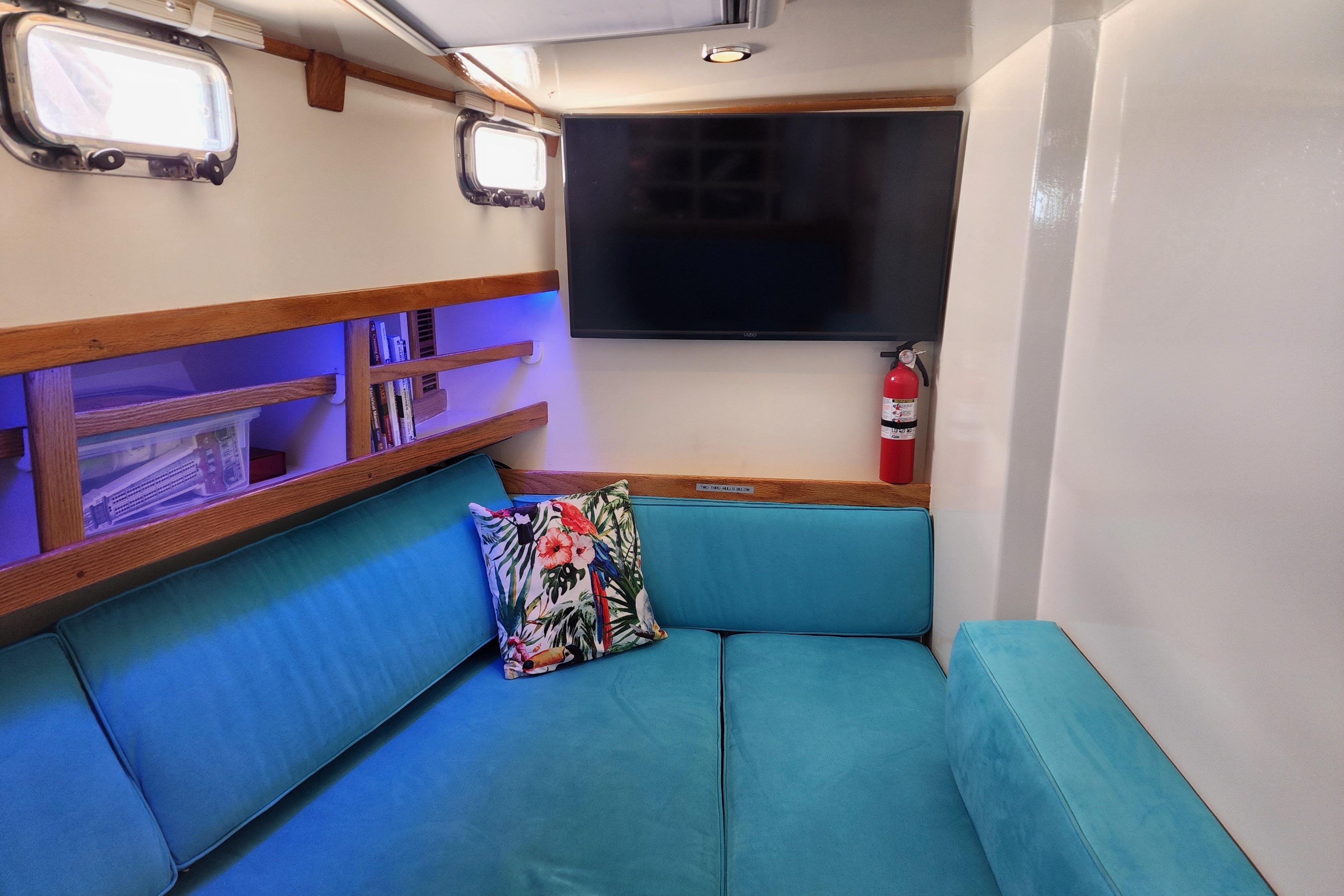 Cozy interior of 1995 Benford Custom Pilothouse Cutter with turquoise seating and tropical pillow.