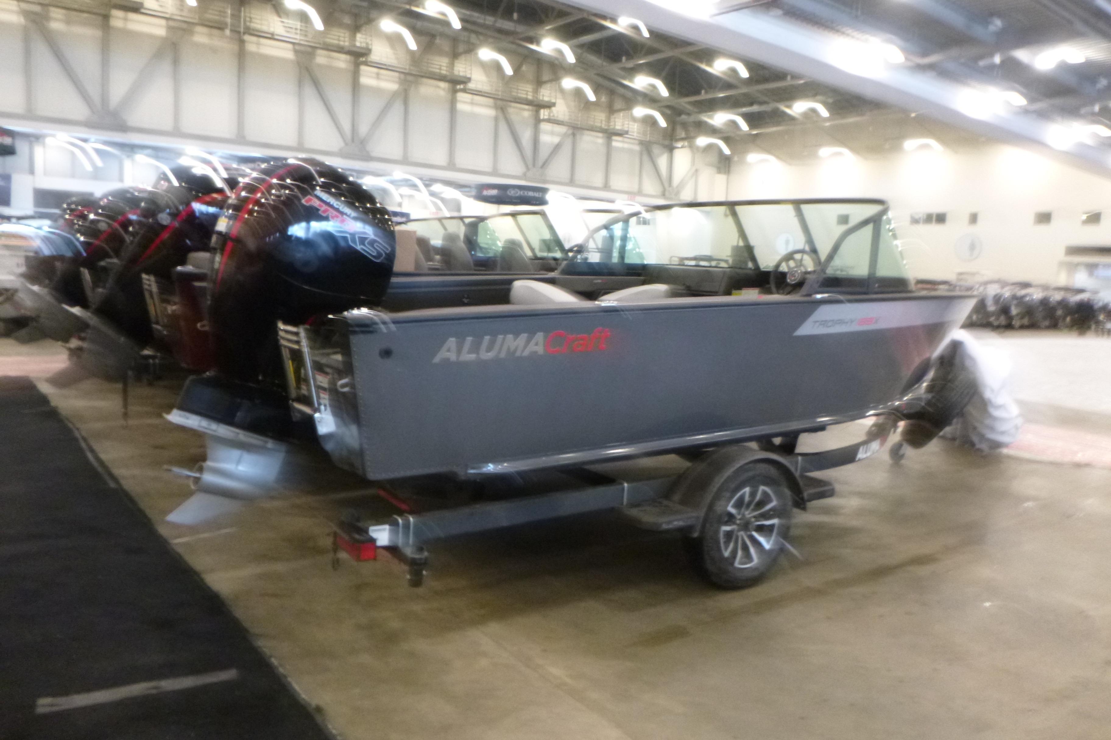 2025 Alumacraft Trophy 185X Sport boat displayed indoors on a trailer.