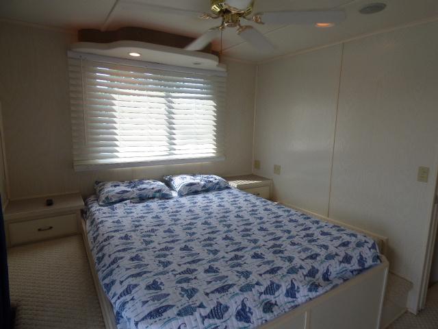 2003 Sunstar 16x65 houseboat bedroom with bed, window blinds, and ceiling fan.