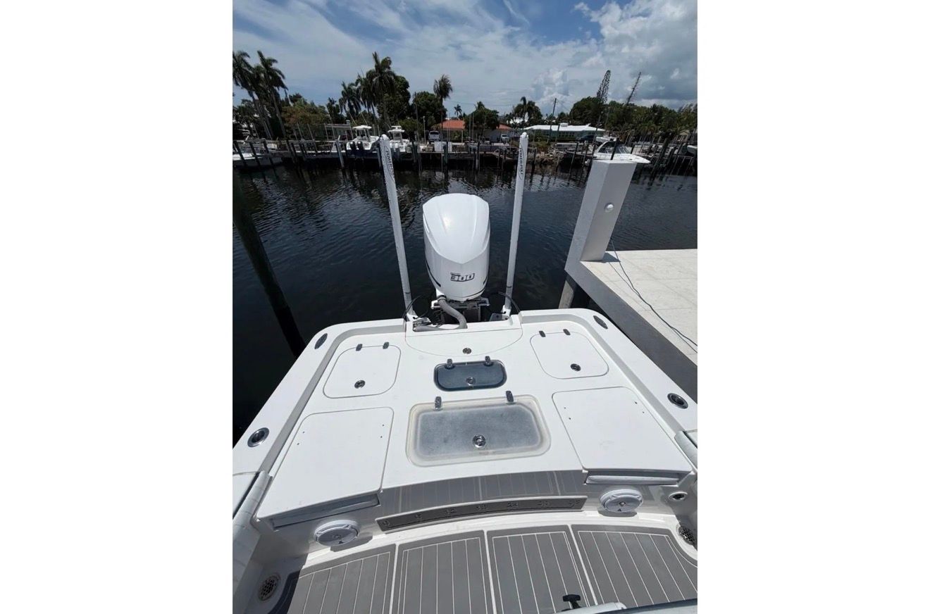 The image shows the stern of a 2016 Contender 25 Bay boat docked at a pier.