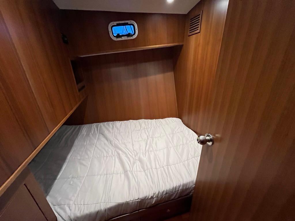 Cozy cabin interior of 2025 Bracewell 41 yacht with wooden paneling and small window.