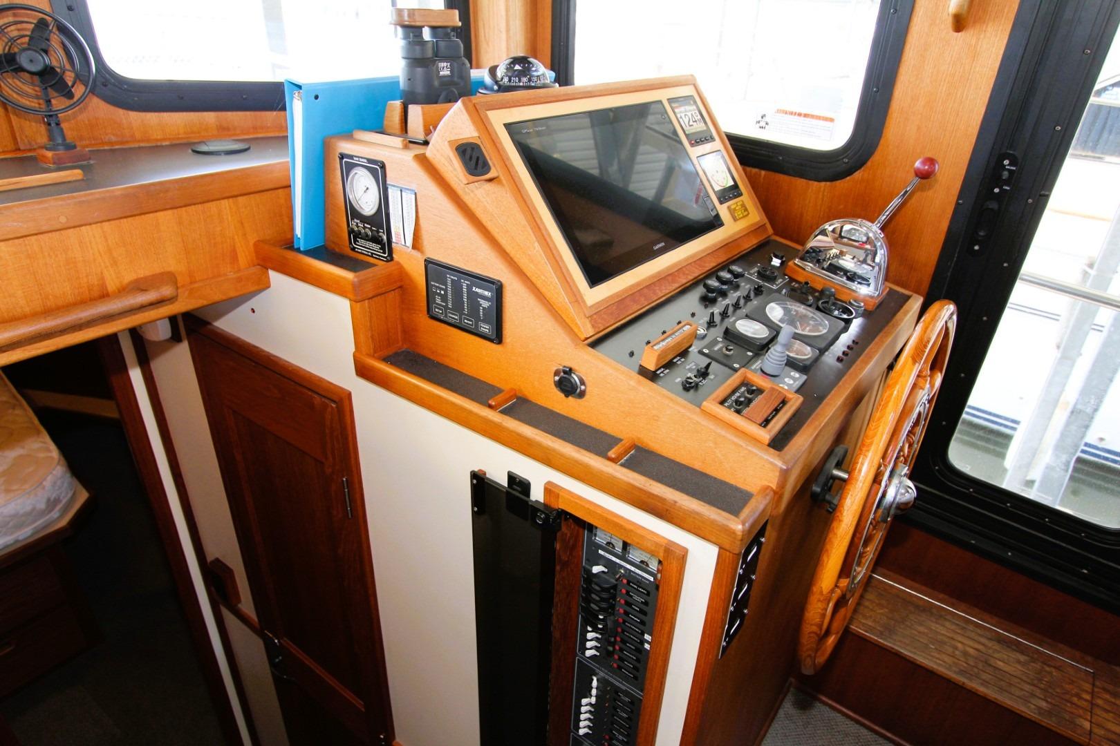 Cabin interior of 2002 Nordic Tug 37 with wooden helm and navigation controls.