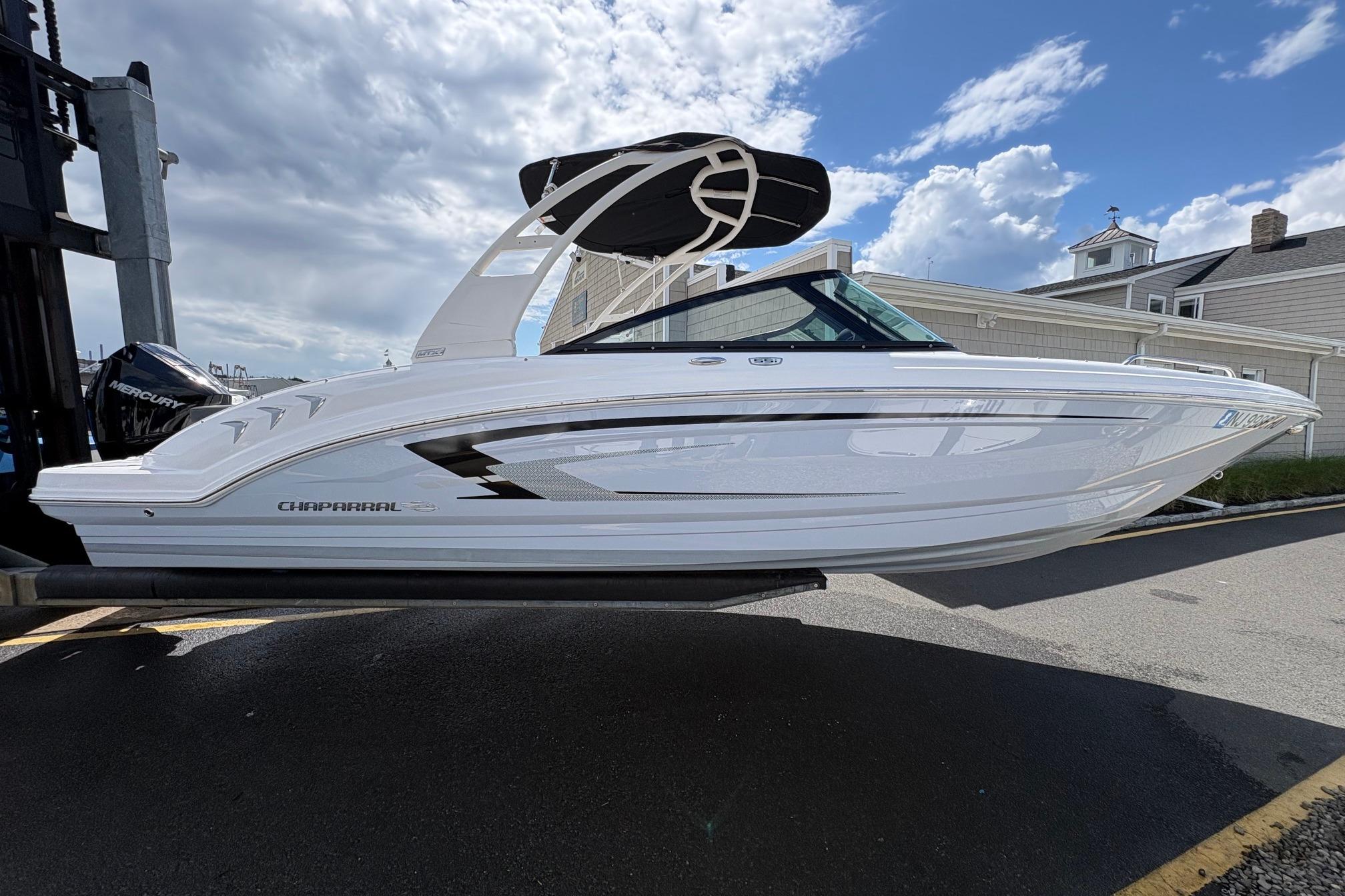 2026 Chaparral 23 SSi OB boat displayed outdoors under a partly cloudy sky.
