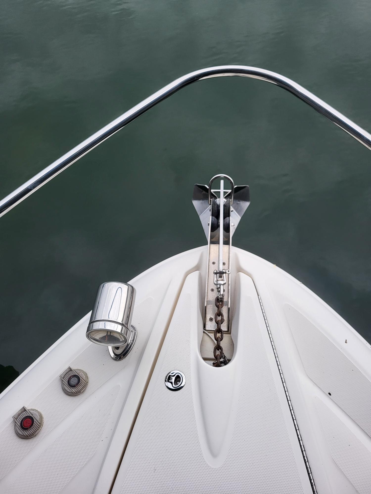 Bow of 2009 Sea Ray 310 Sundancer with anchor and railing over water.