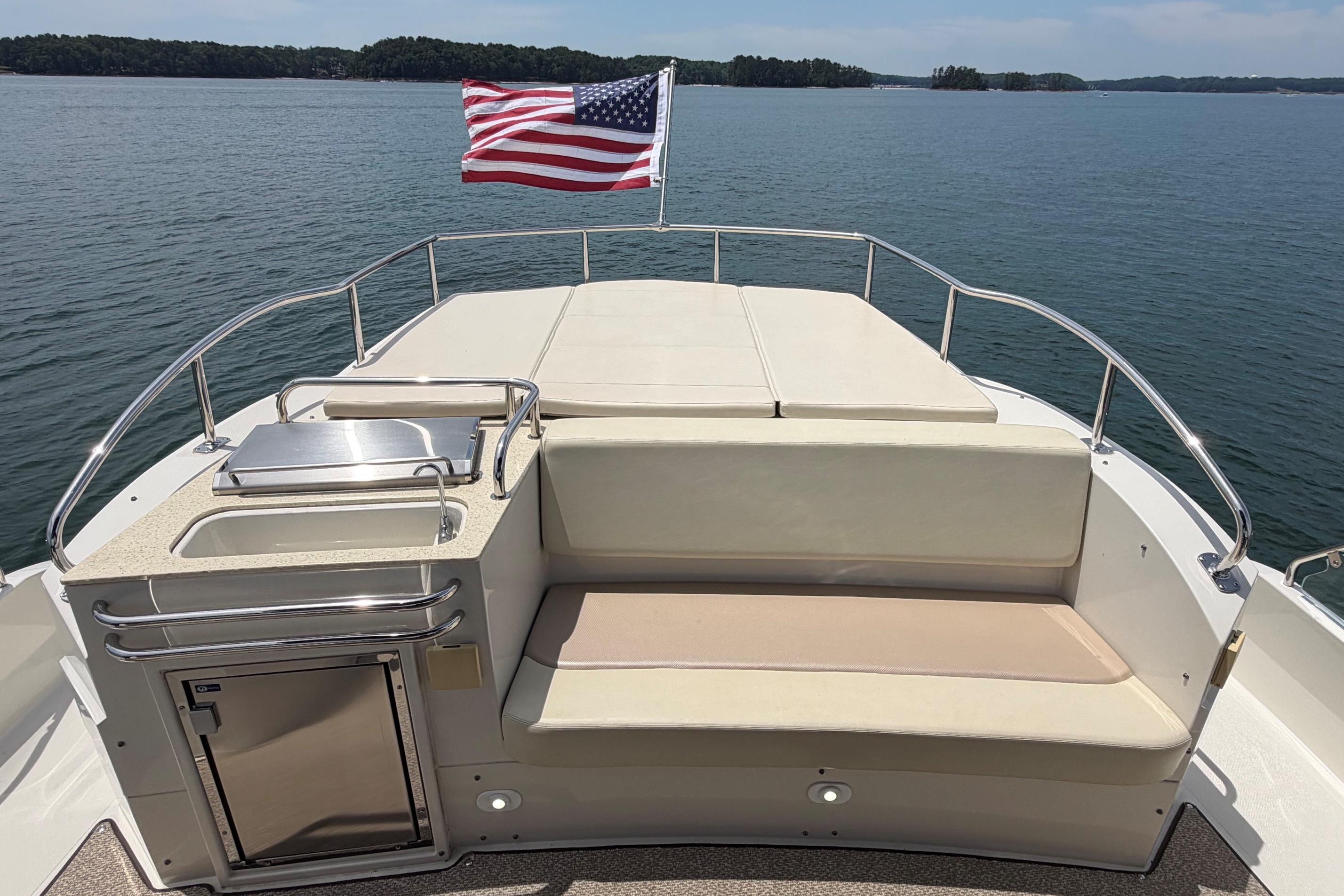 2011 Carver 44 Sojourn yacht deck with seating, grill, and American flag on a lake.