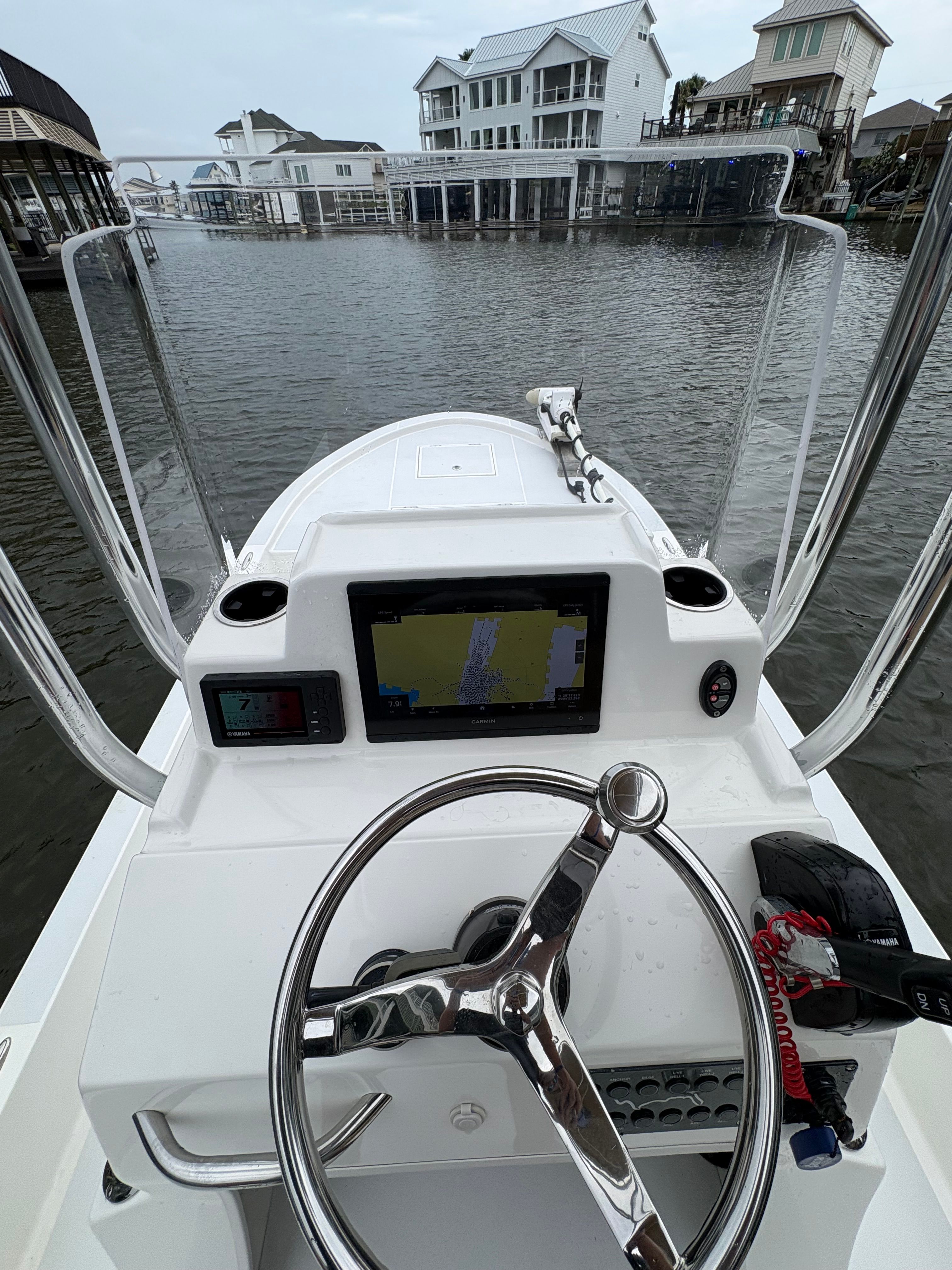 The cockpit of a Shallow Sport 24 Sport boat overlooking water and houses.