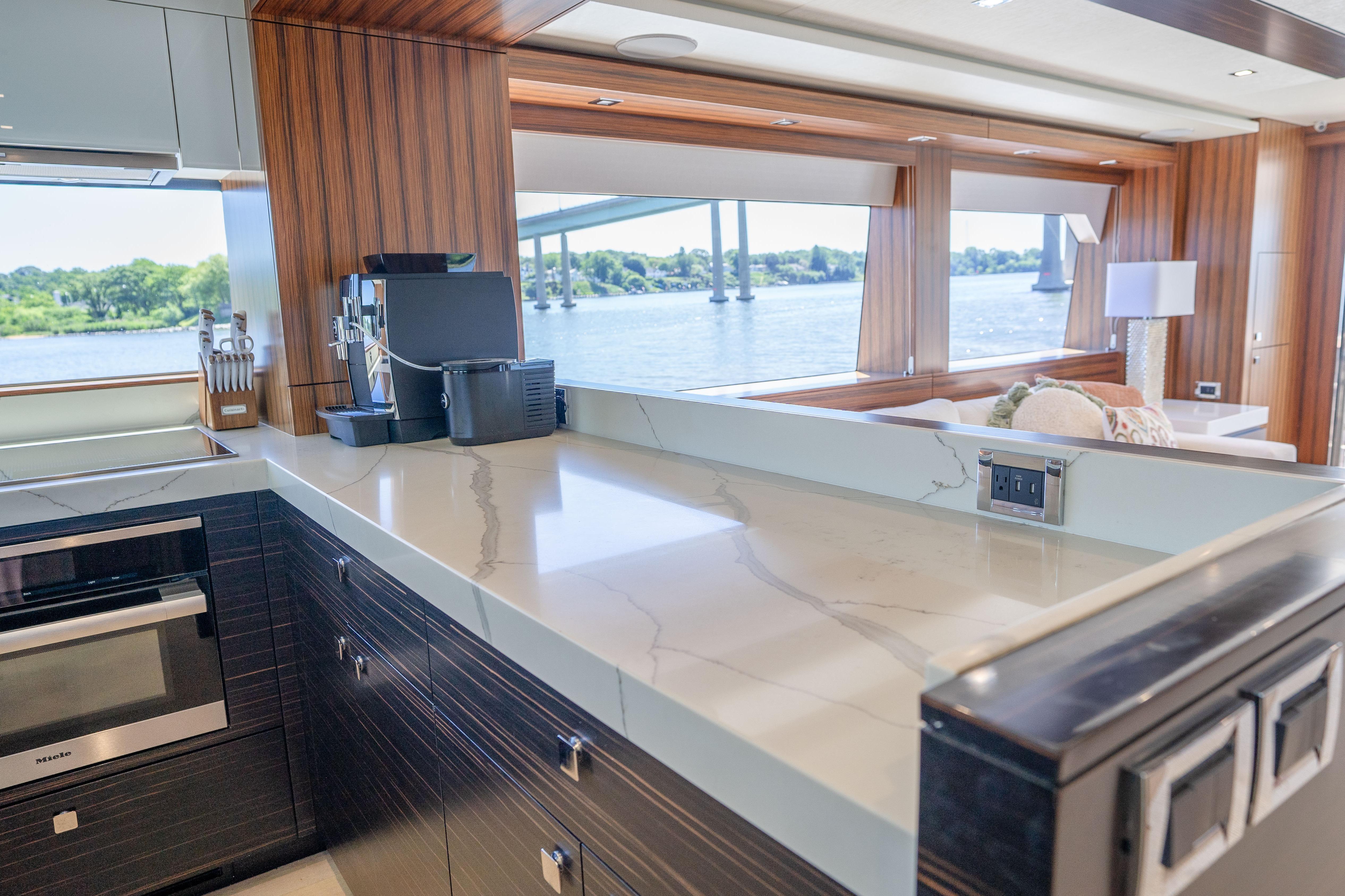 Luxurious kitchen interior of 2021 Hatteras M75 Panacera yacht with scenic water view.