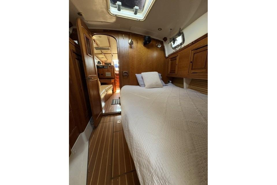 Interior cabin of 2002 Saga 43 yacht with wooden finish and cozy bedding.