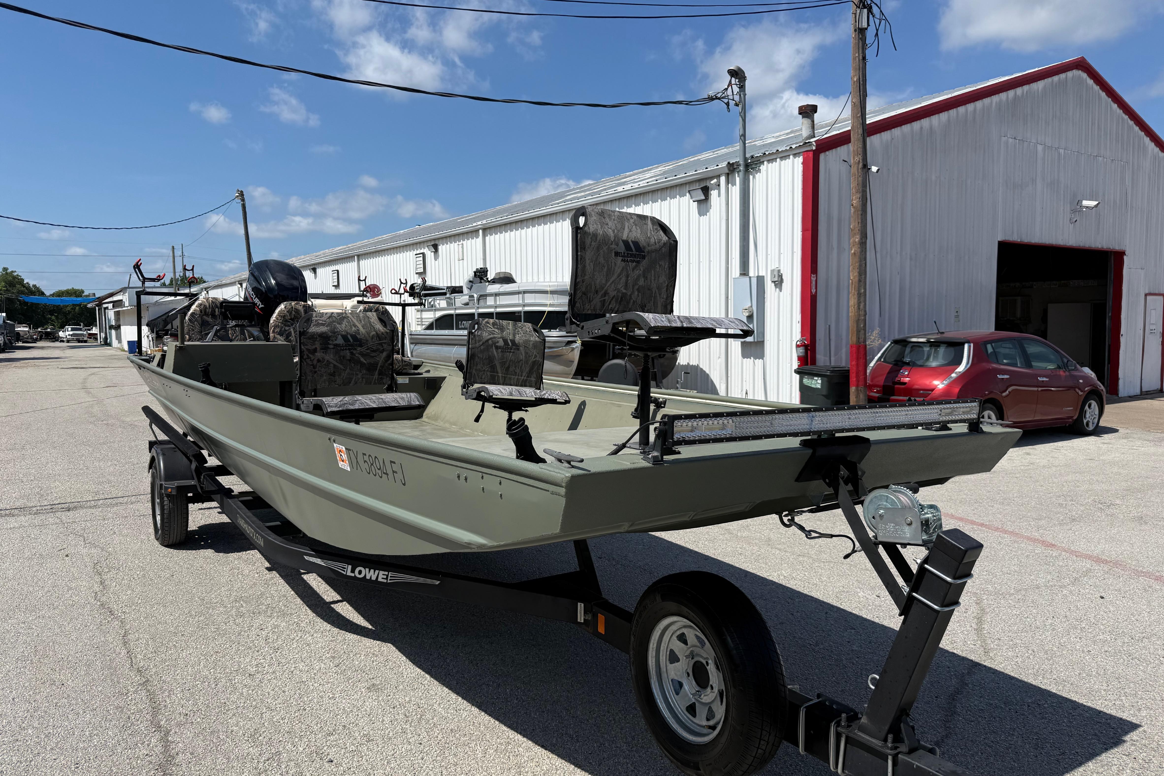 A 2020 Lowe Roughneck 2070 Big River boat on a trailer in front of a building.