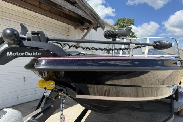 2016 Triton 216 Fishunter boat with MotorGuide trolling motor, parked outdoors under a blue sky.
