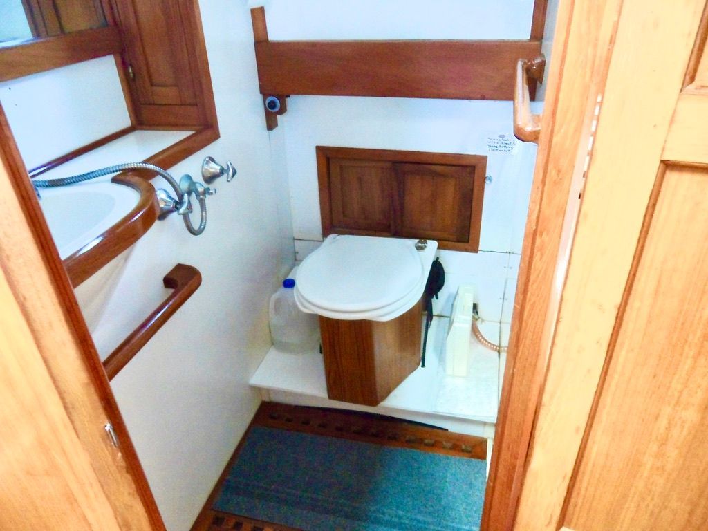 1976 CHB Trawler bathroom with wooden accents, sink, and toilet.