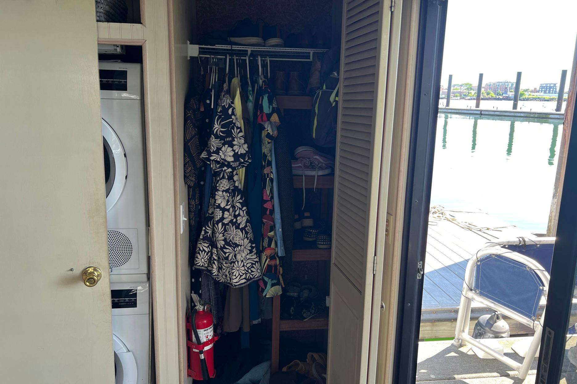 Interior of a 1993 Sumerset houseboat closet with clothes, washer, and fire extinguisher.