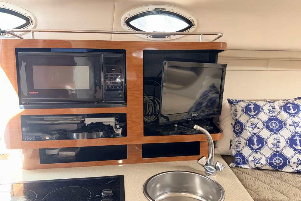 Interior of 2001 Monterey 282 Cruiser with microwave, TV, and nautical-themed pillow.
