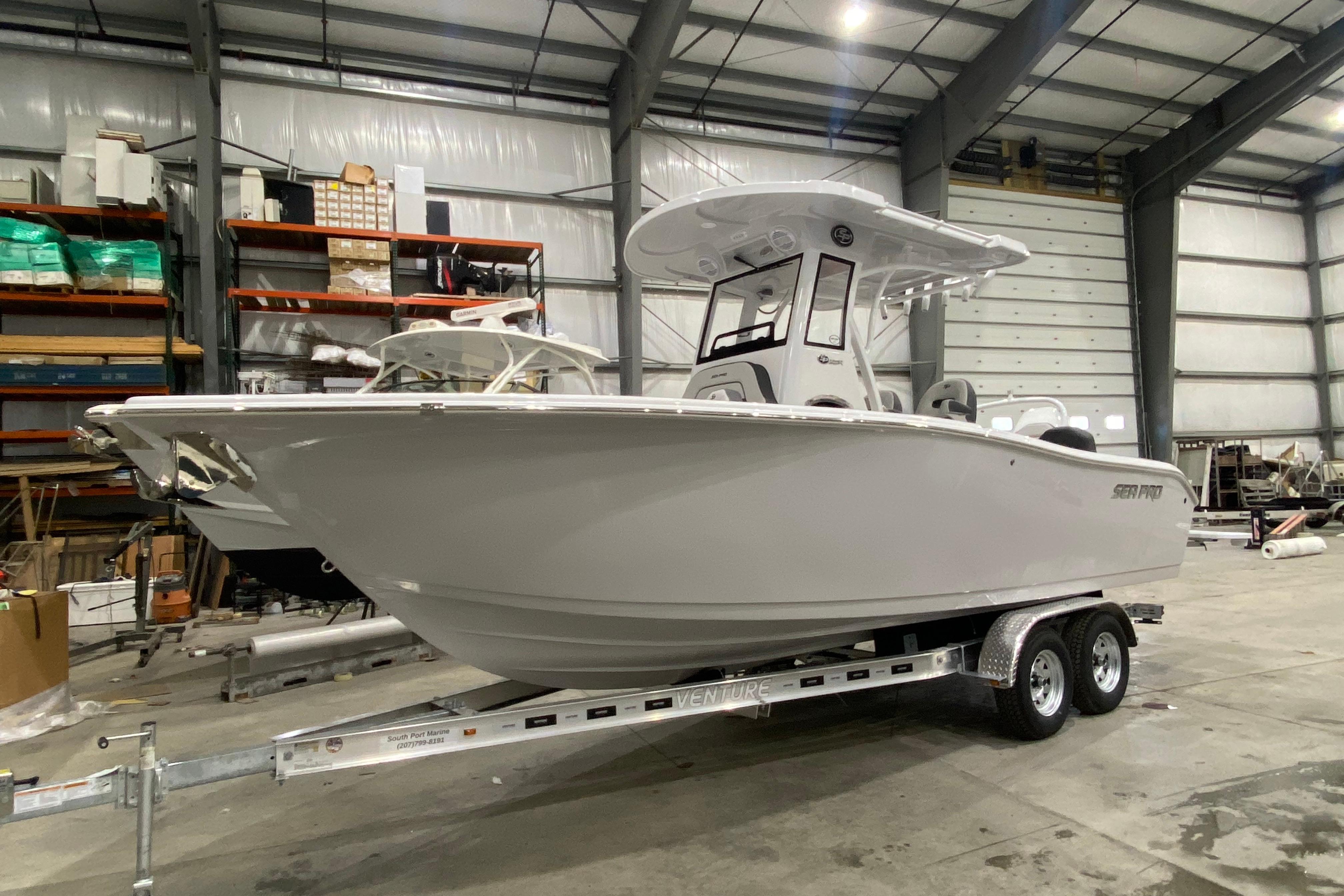 2027 Sea Pro 245FLXR Sandbar boat on trailer in warehouse setting.
