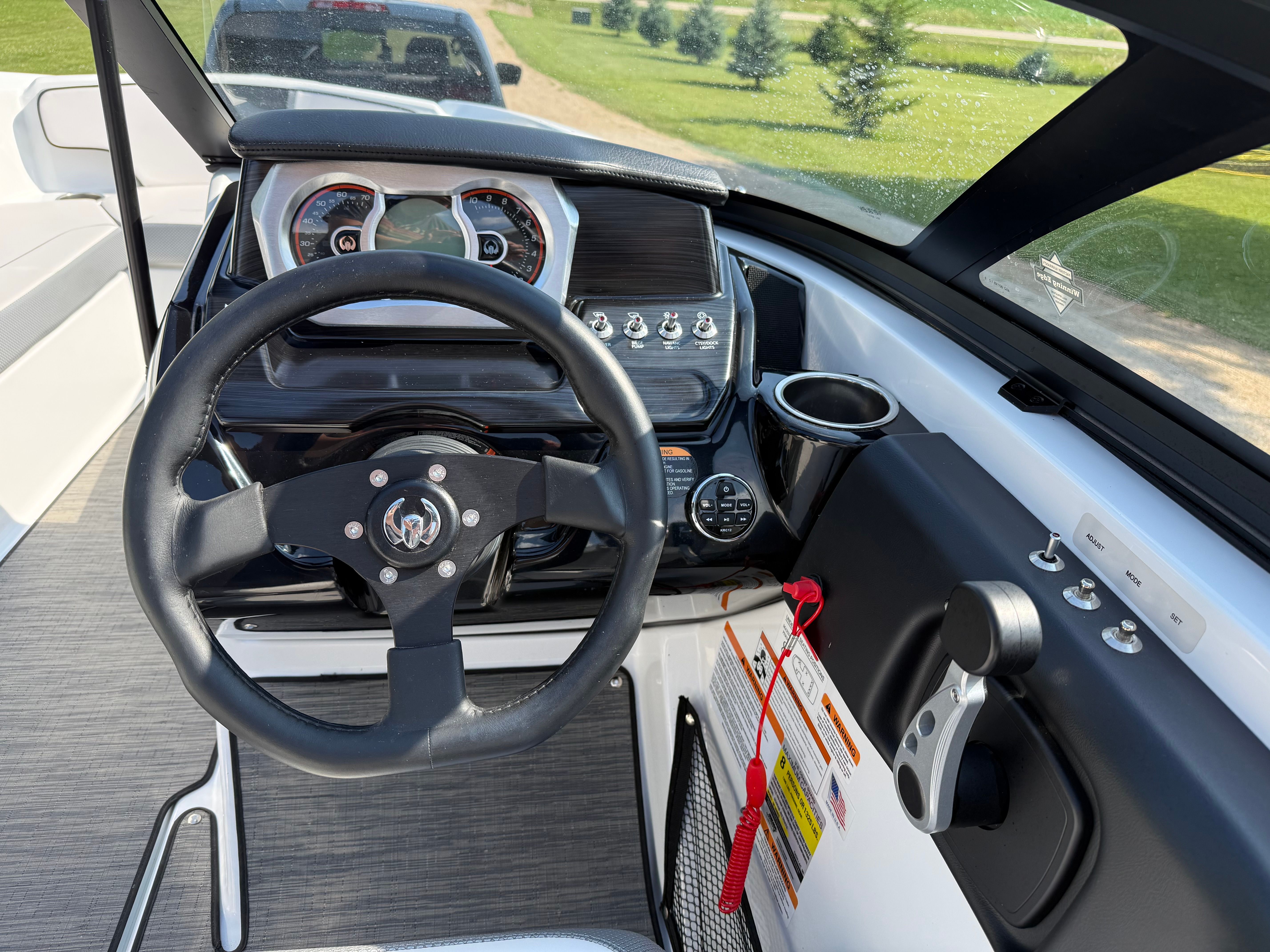 The image shows the cockpit of a 2023 Scarab 195 ID boat with a modern steering wheel and dashboard.