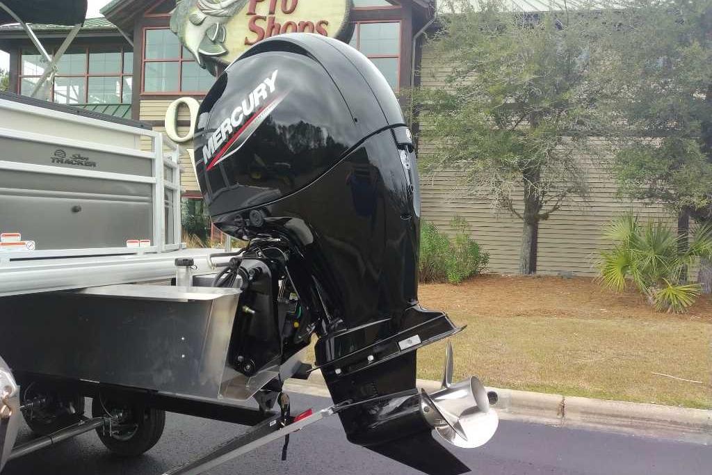 2026 Sun Tracker Fishin' Barge 22 DLX with Mercury outboard motor, parked outdoors.