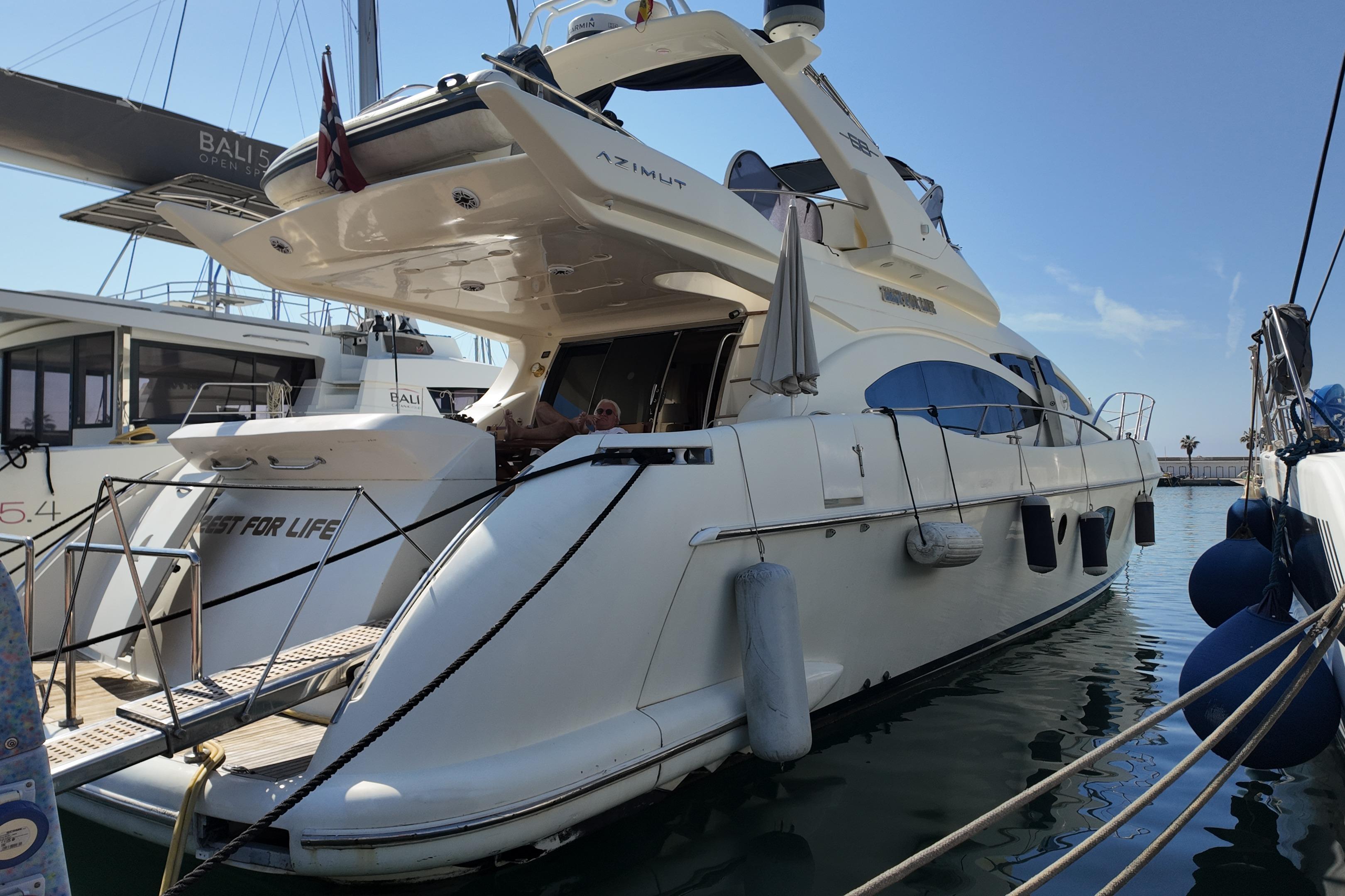 Luxury 2006 Azimut 68E yacht docked in marina, featuring sleek design and spacious deck.