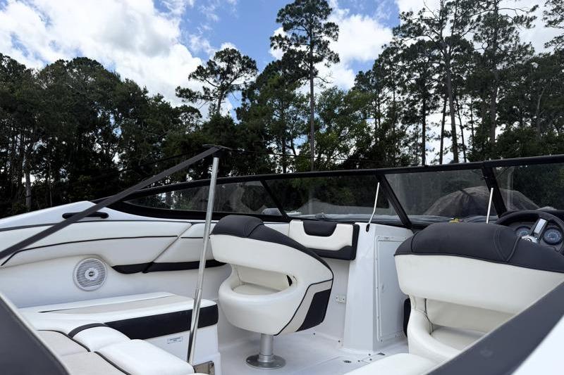 2017 Yamaha Boats SX210 interior with white seating, surrounded by trees and blue sky.