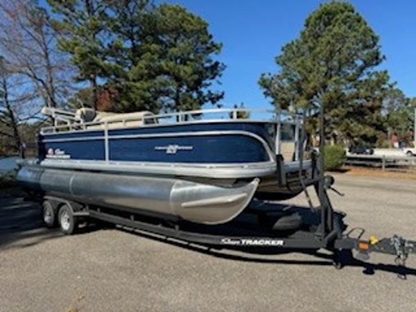 2025 Sun Tracker Fishin' Barge 22 DLX on trailer, parked outdoors.