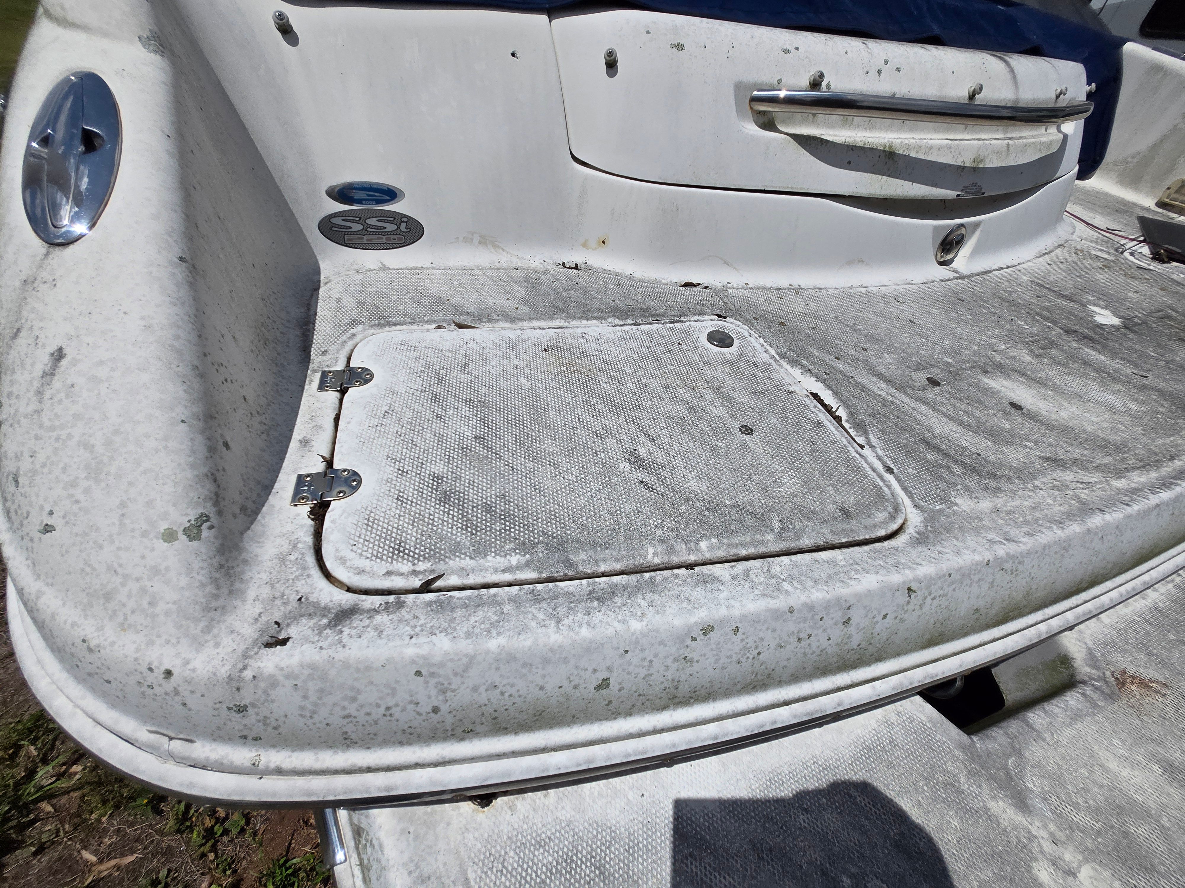The image shows the stern of a 2006 Chaparral 220 SSi boat with a worn deck.