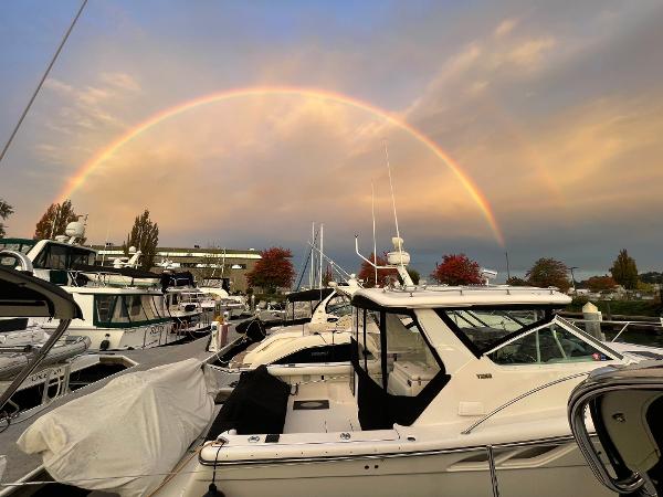A 2003 Tiara Yachts 3500 Open docked under a vibrant rainbow at sunset.
