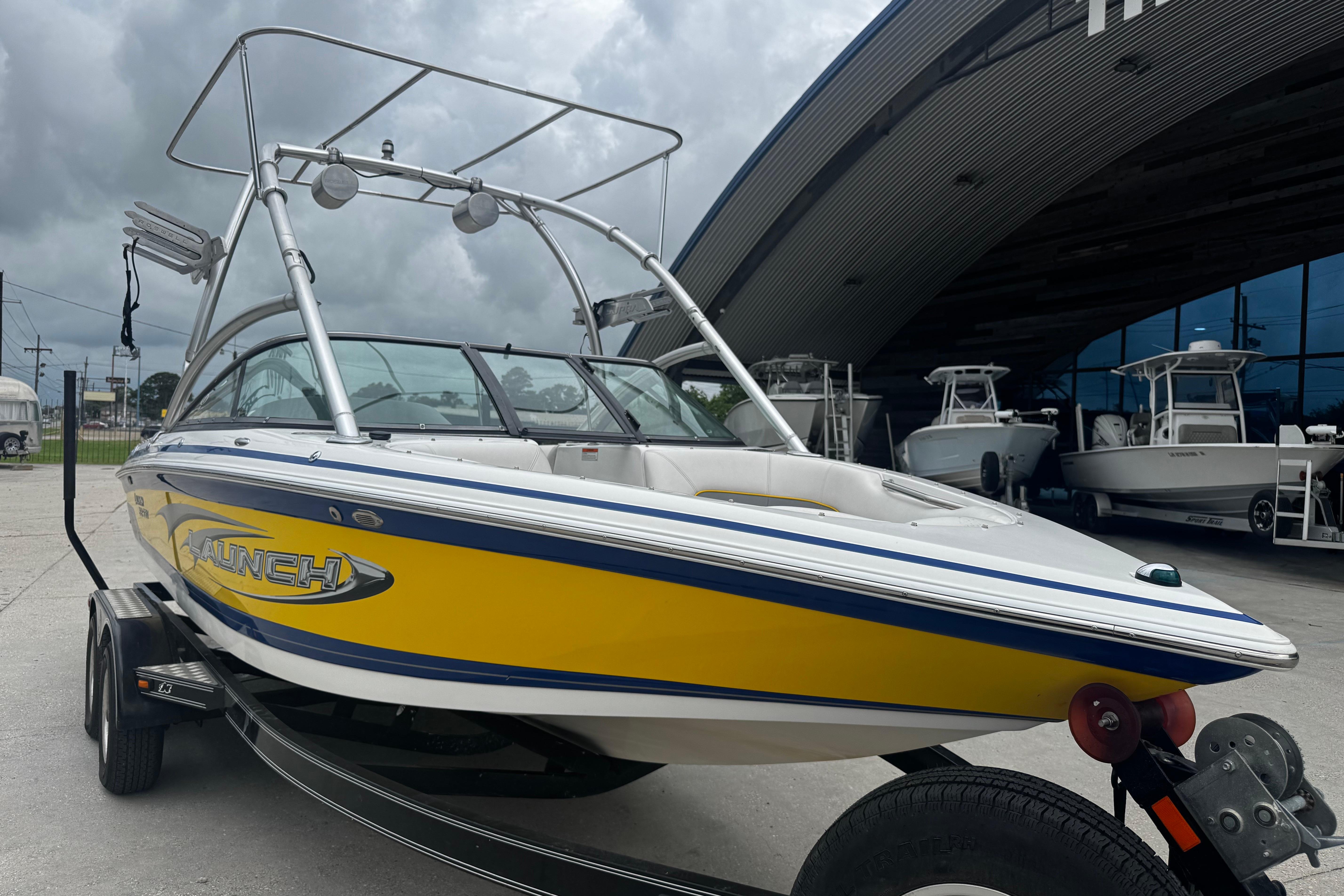 2006 Supra Launch 22 SSV boat with yellow detailing, parked outside a showroom.