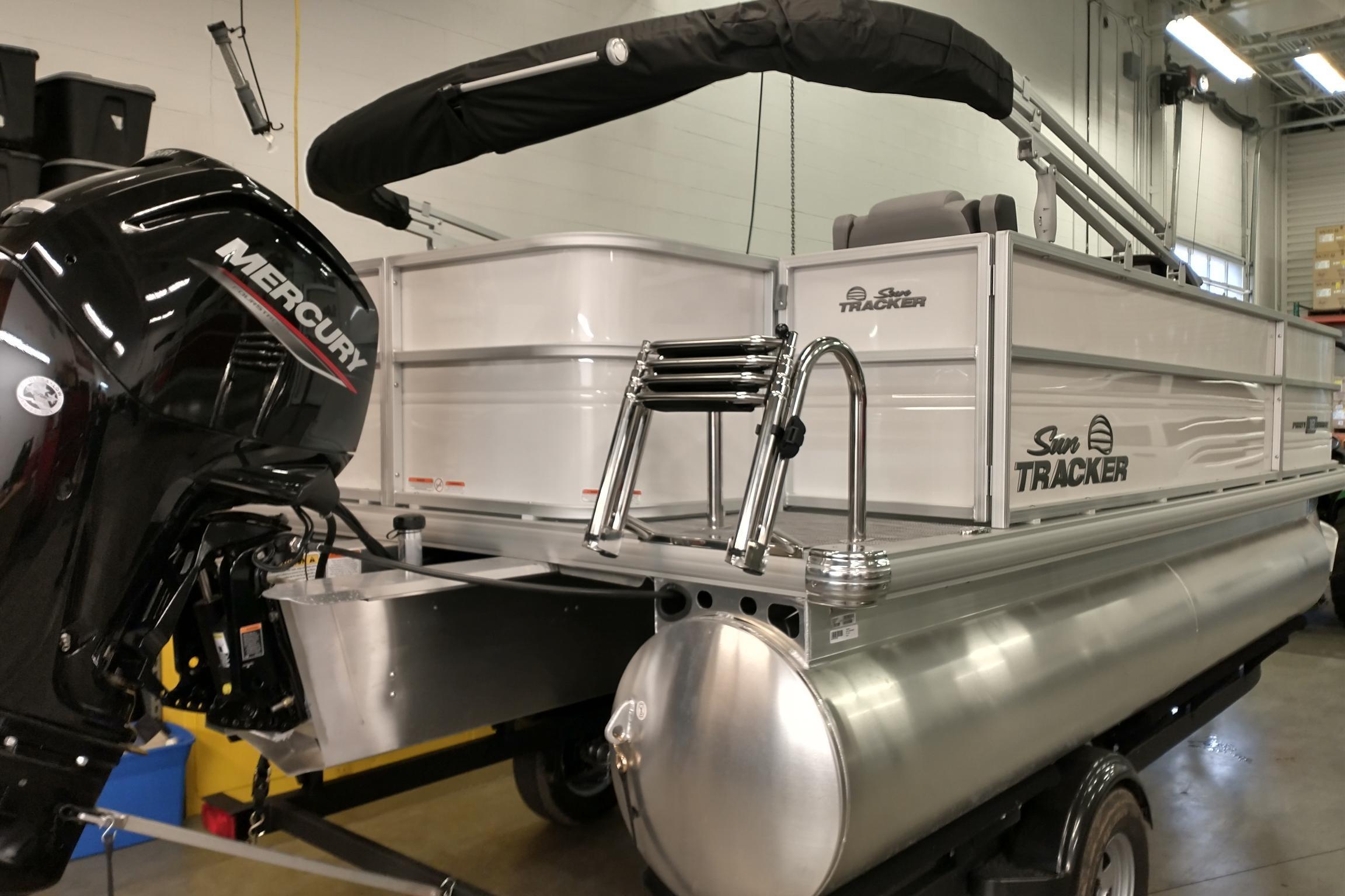 2026 Sun Tracker Party Barge 18 DLX pontoon boat with Mercury engine in a showroom.