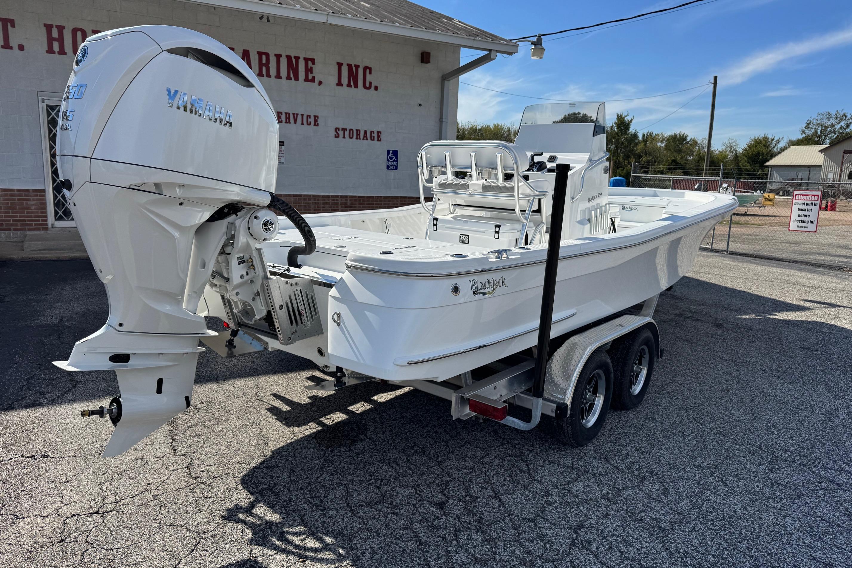 2026 BlackJack 256 Bay boat on trailer with Yamaha outboard motor, parked outside a marine store.