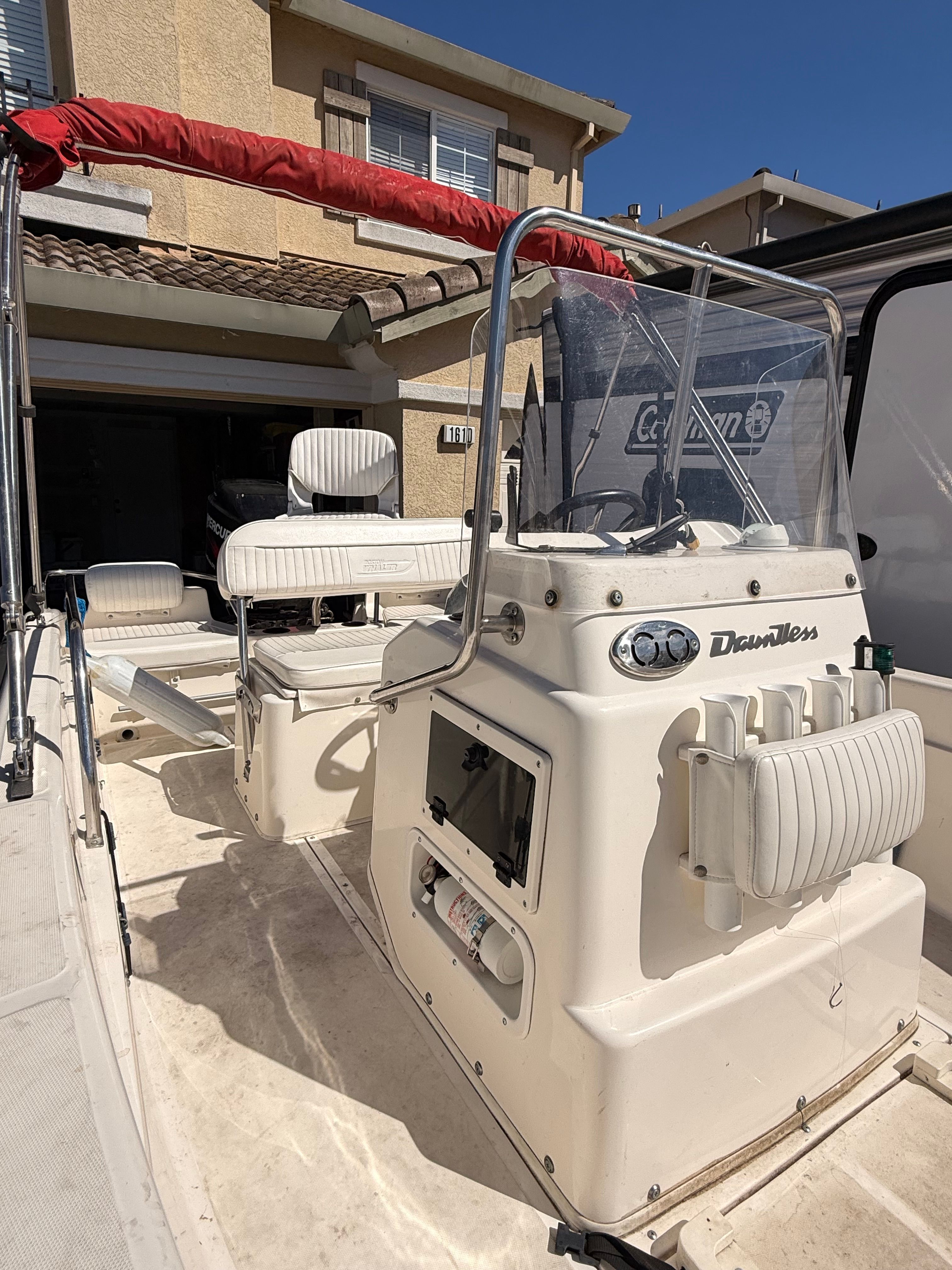 The image shows the cockpit of a 2002 Boston Whaler 160 Dauntless. It features a white console with a red sunshade.