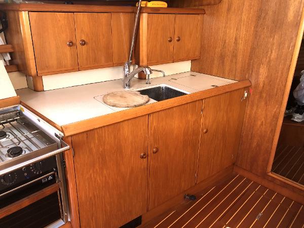 2001 Jeanneau 45.2 yacht kitchen with wooden cabinets and sink.
