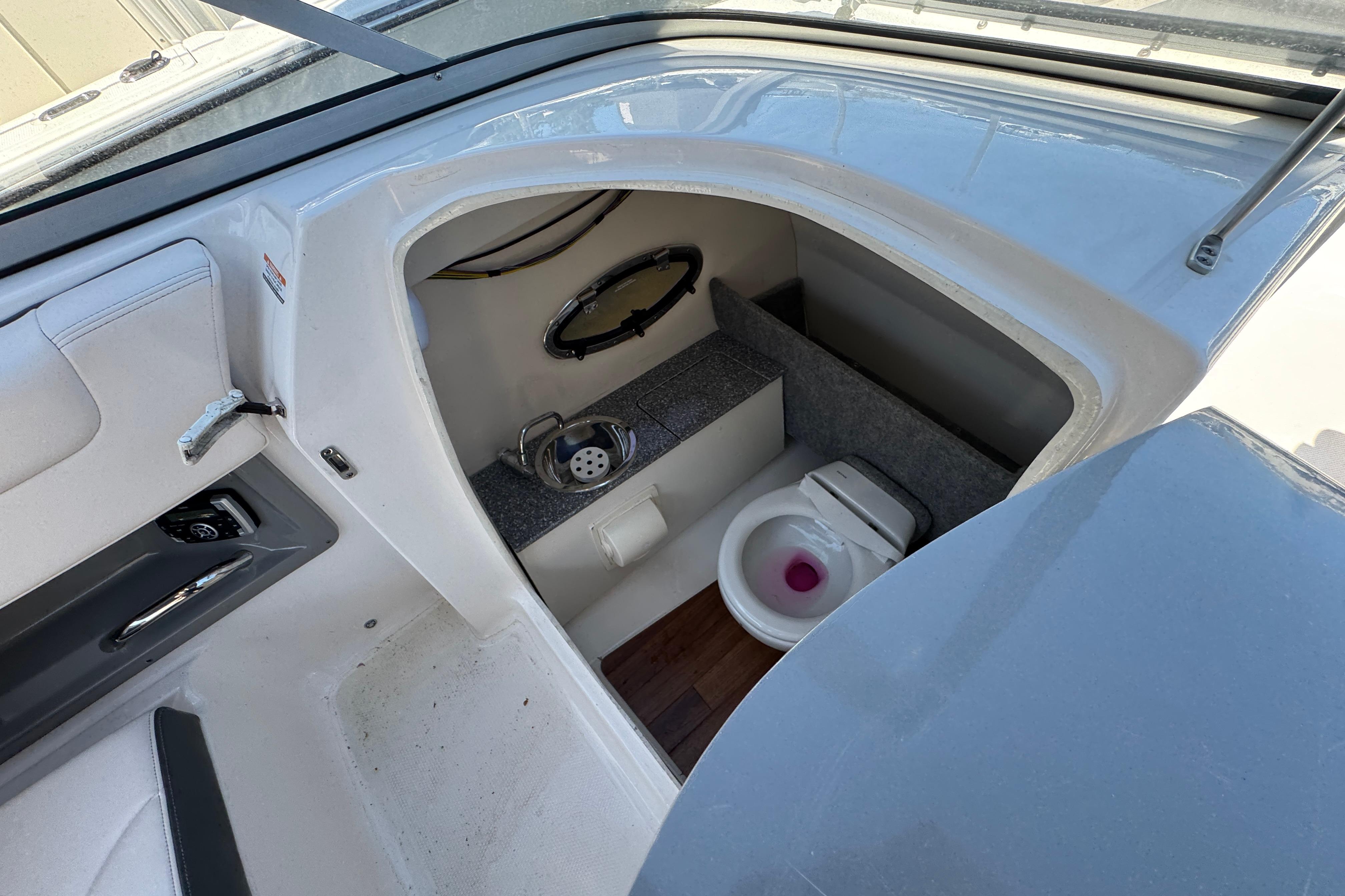 Interior of 2018 Chaparral 250 Suncoast boat featuring a compact marine toilet.