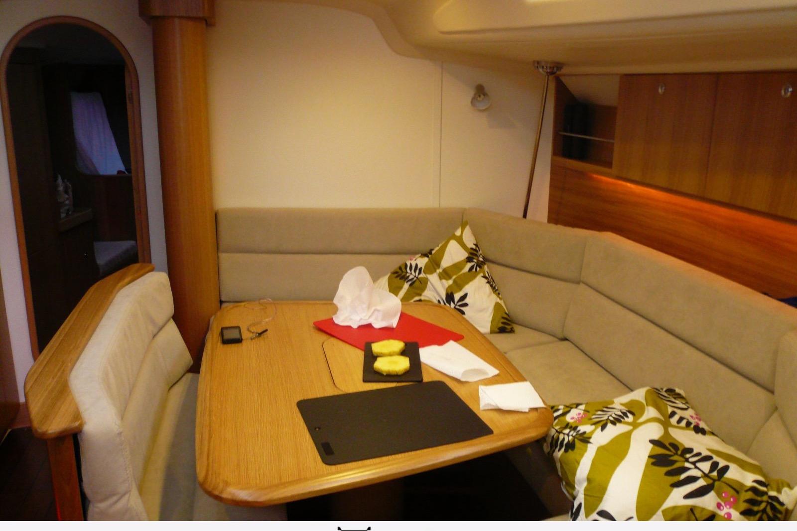 Cozy yacht interior with cushioned seating, wooden table, and decorative pillows, Maxi 1300, 2010 model.