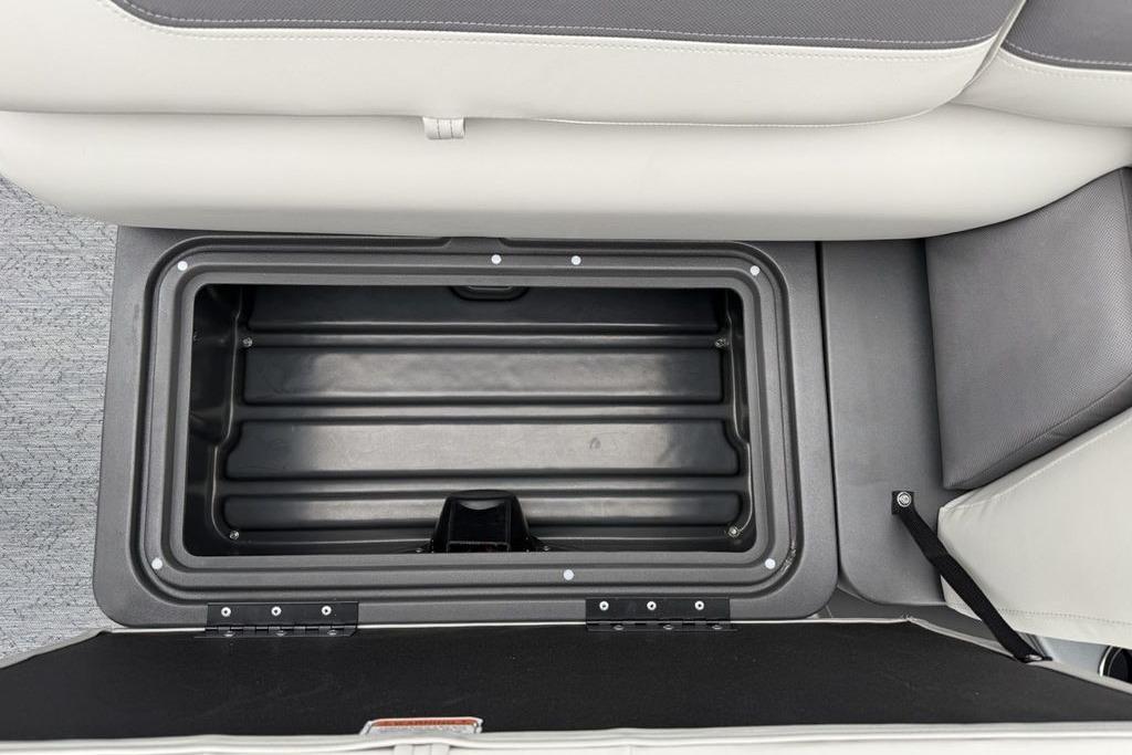 Storage compartment in 2026 Sun Tracker Fishin' Barge 20 DLX boat, featuring cushioned seating.