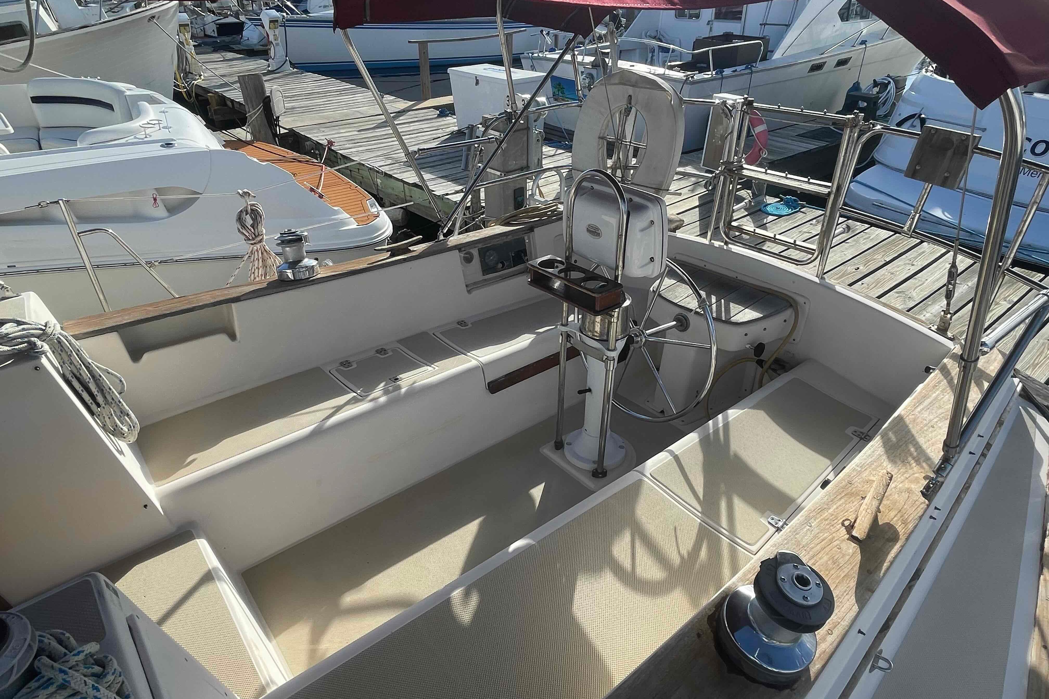 1989 Island Packet 35 sailboat cockpit with steering wheel, docked at marina.