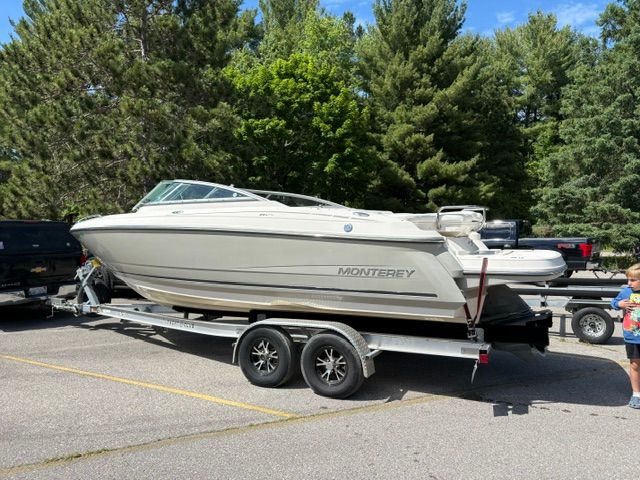 A 2009 Monterey 234FS boat on a trailer, surrounded by trees.
