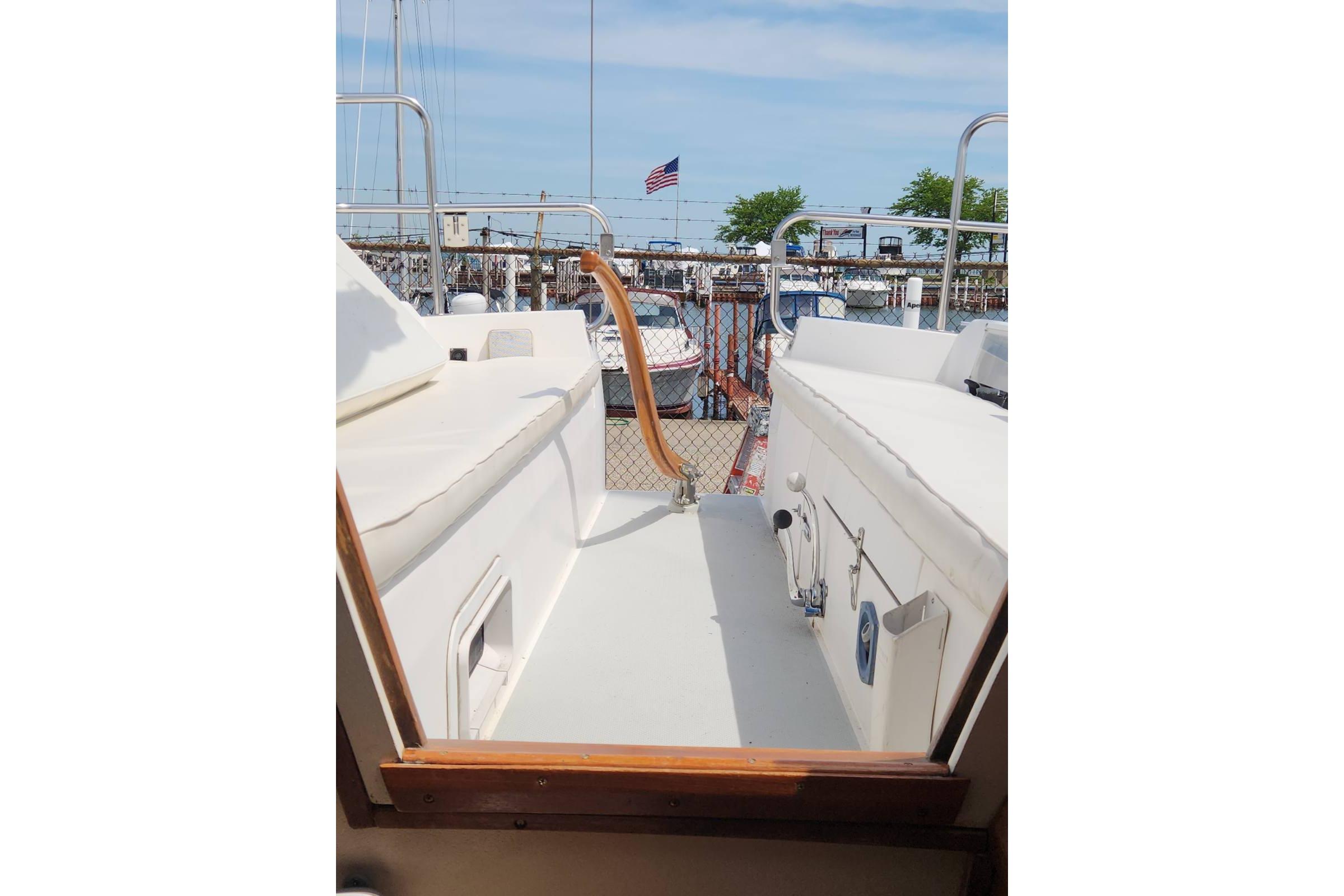 1990 Catalina Capri sailboat cockpit view at marina with American flag in background.