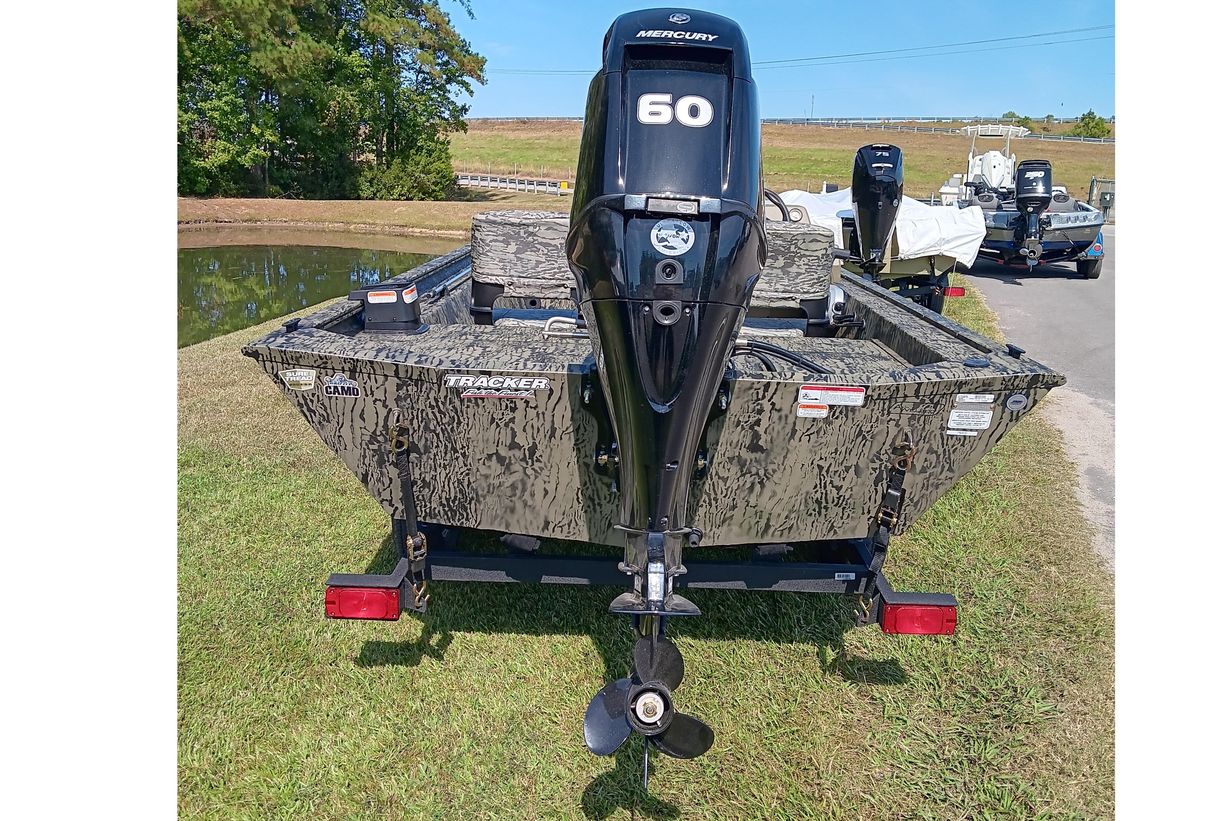 2026 Tracker Grizzly 1754 SC boat with Mercury 60 engine, camo design, parked near a pond.