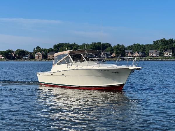 A 1985 Viking 35 Express boat cruising on calm water near a shoreline.