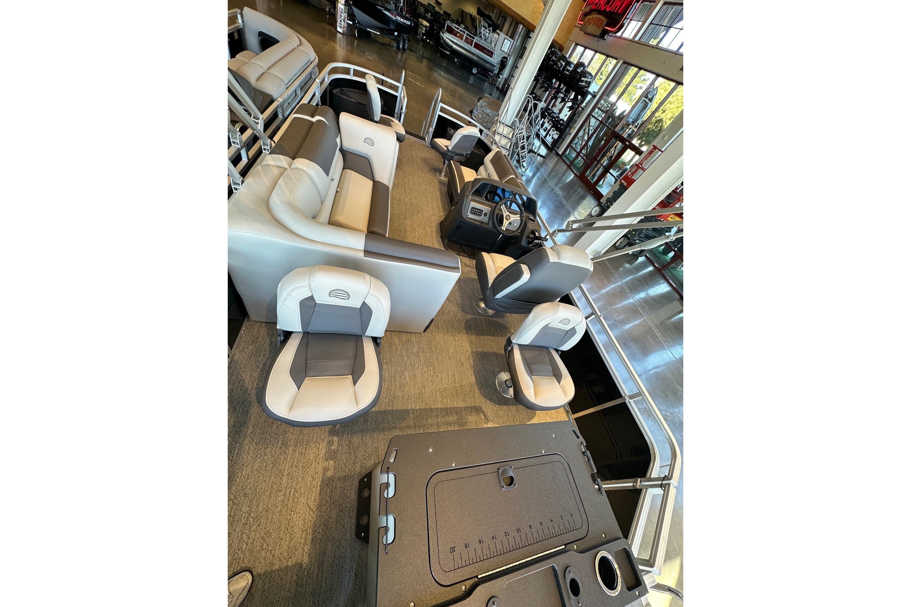 2026 Sun Tracker Fishin' Barge 20 DLX interior with seating and helm in showroom.