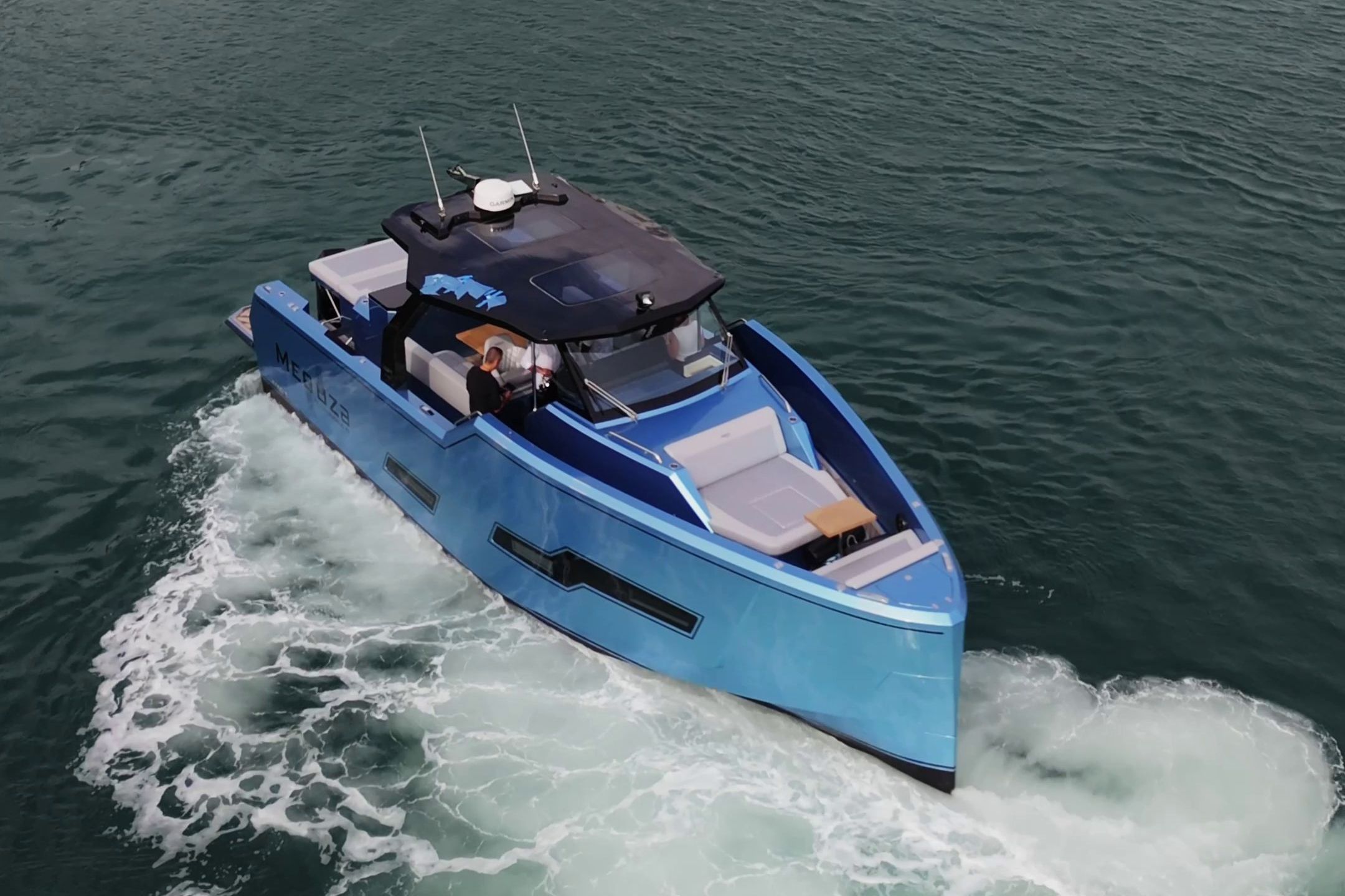 A modern blue motorboat cruising on the water. It features an open deck and sleek design.