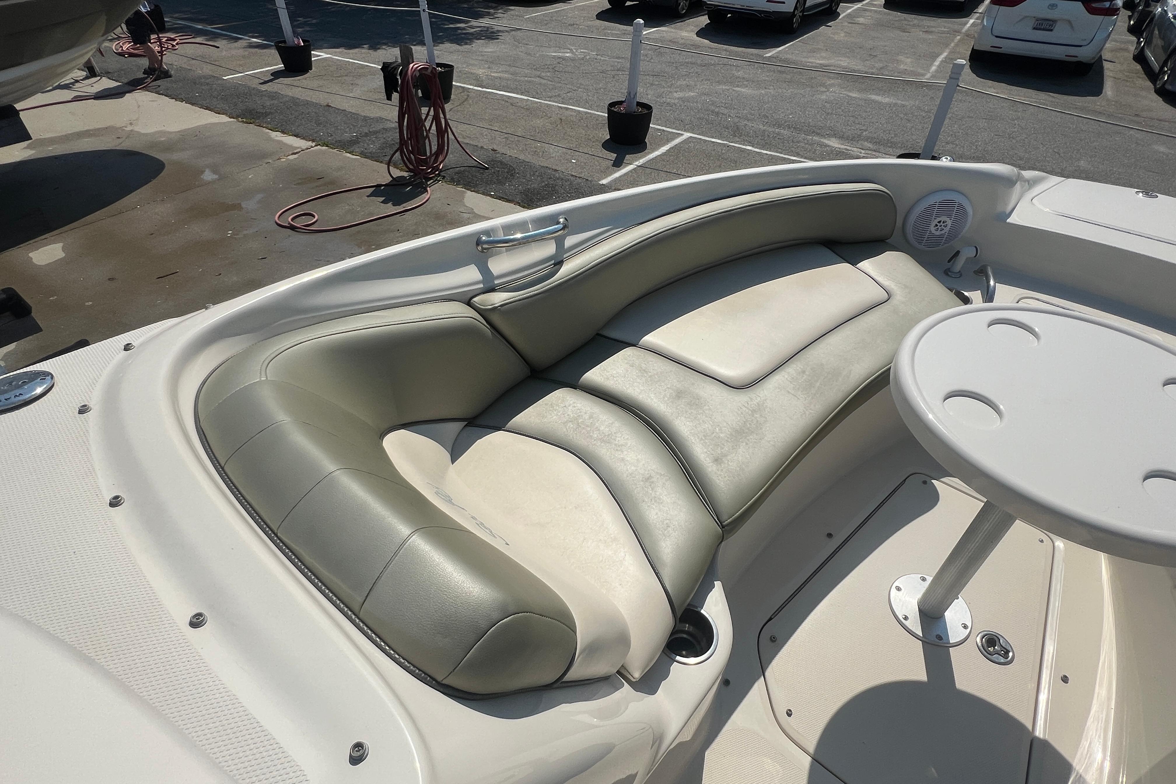 2005 Sea Ray 240 Sundeck interior with cushioned seating and table in a parking lot.