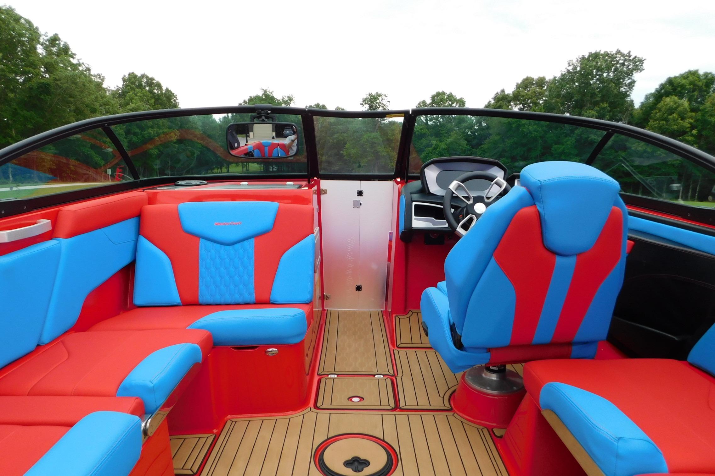 2022 MasterCraft NXT24 boat interior with vibrant red and blue seating, sleek dashboard, and wood flooring.