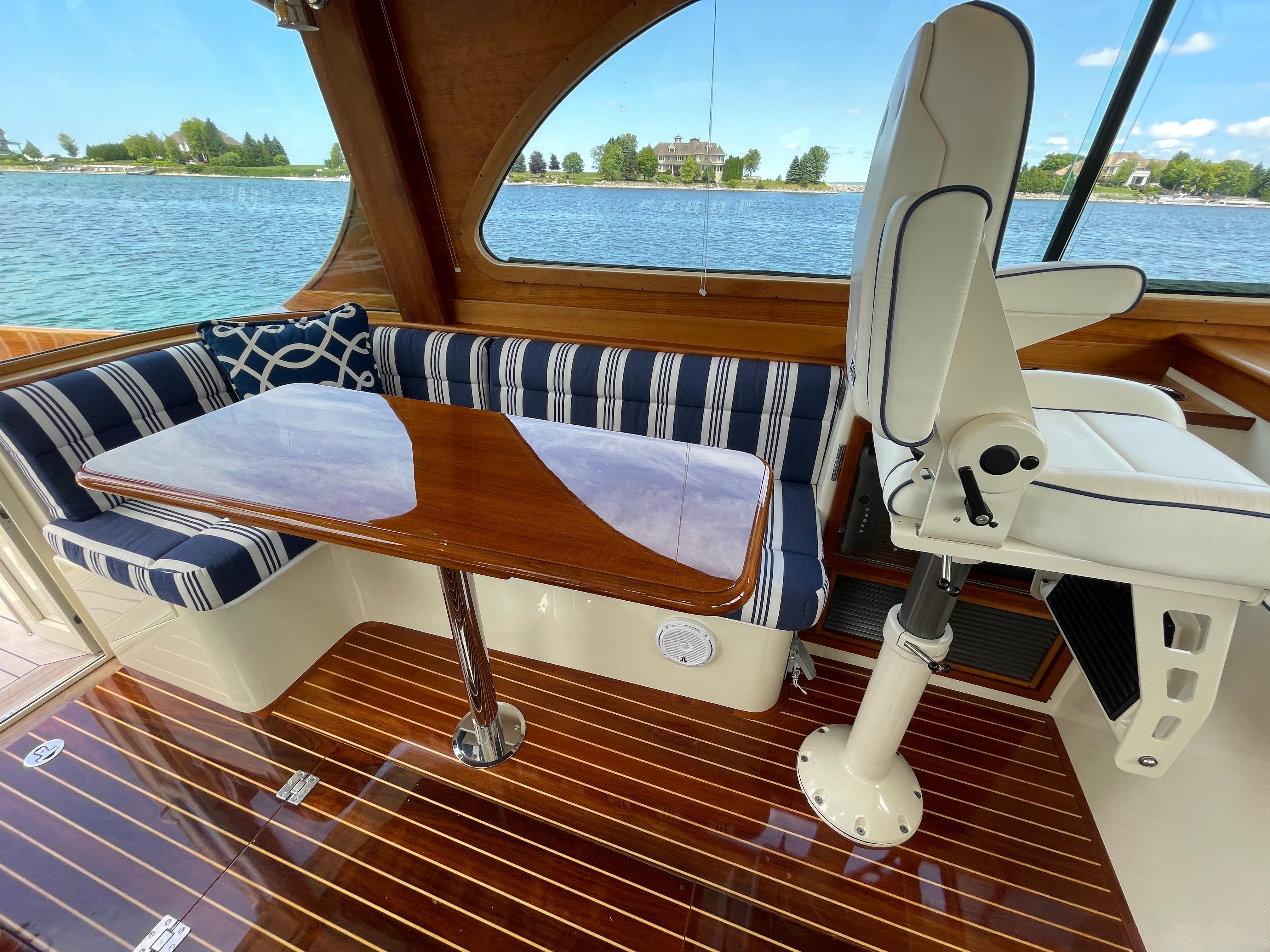 2007 Hinckley Talaria 44 Flybridge interior with striped seating, wooden table, and scenic water view.