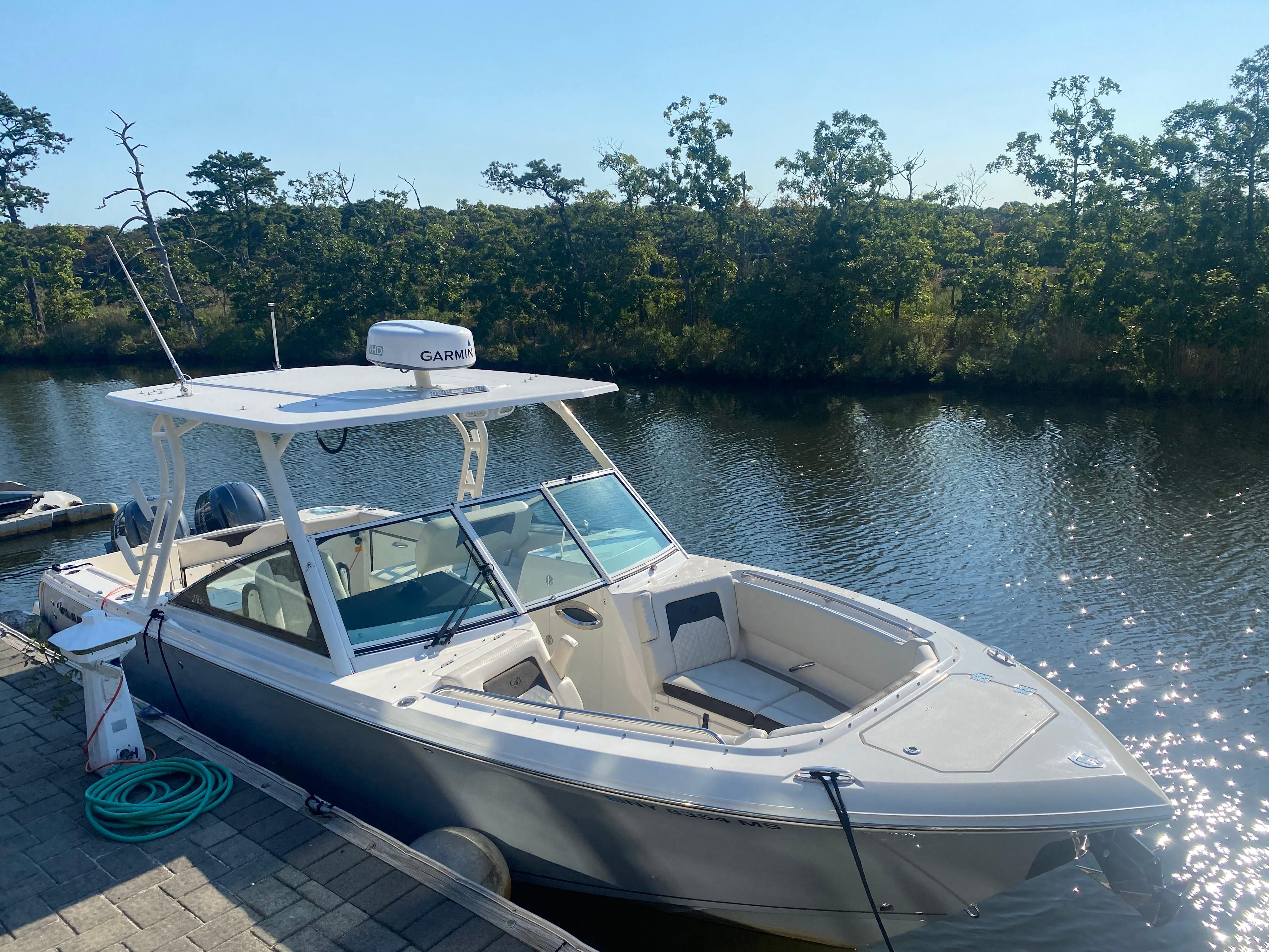 Sailfish 276 DC 2022 boat docked by the river in sunlight.