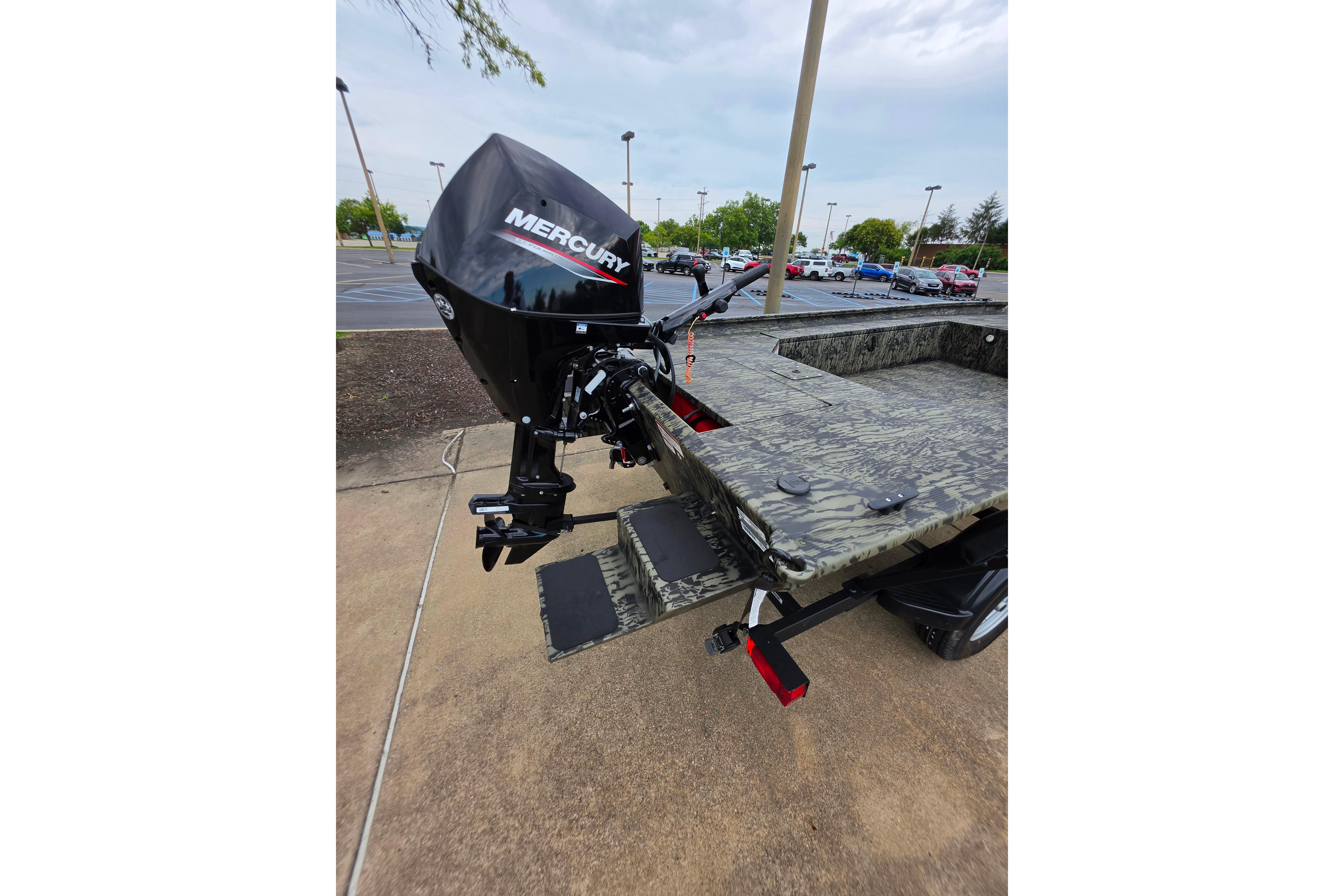 2026 Tracker Grizzly 1654 T Sportsman boat with Mercury outboard motor in parking lot.