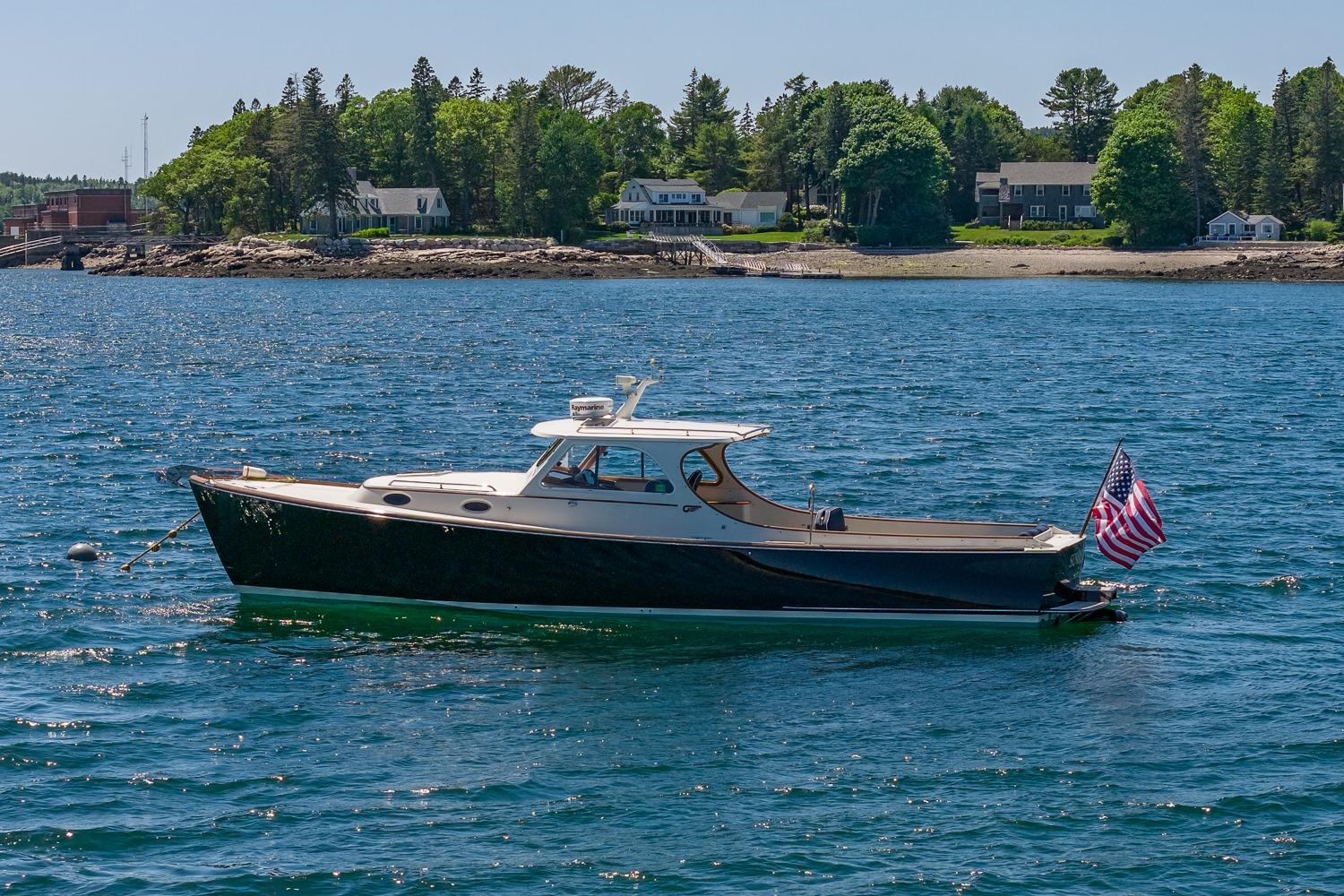 2001 Hinckley Picnic Boat 36 Classic on serene water with coastal backdrop.