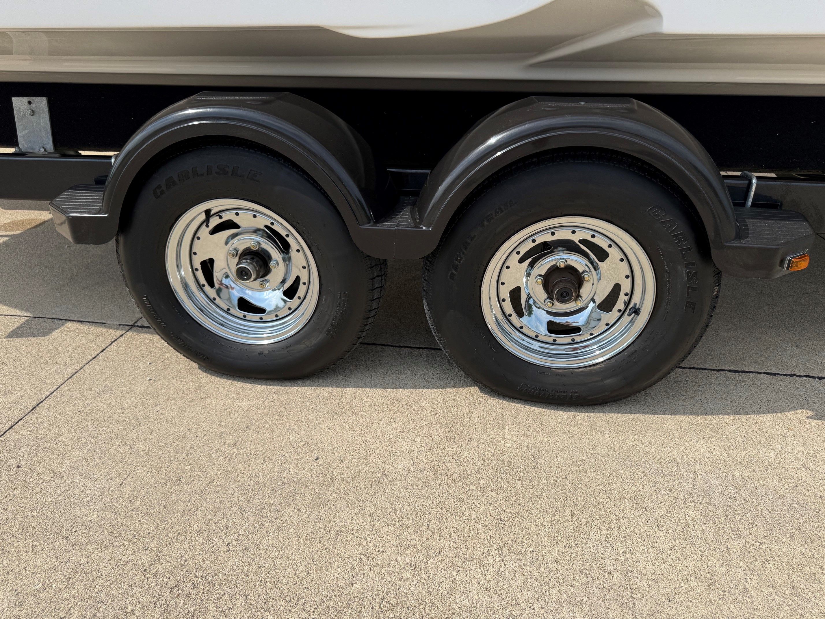 Close-up of two trailer wheels on a concrete surface.