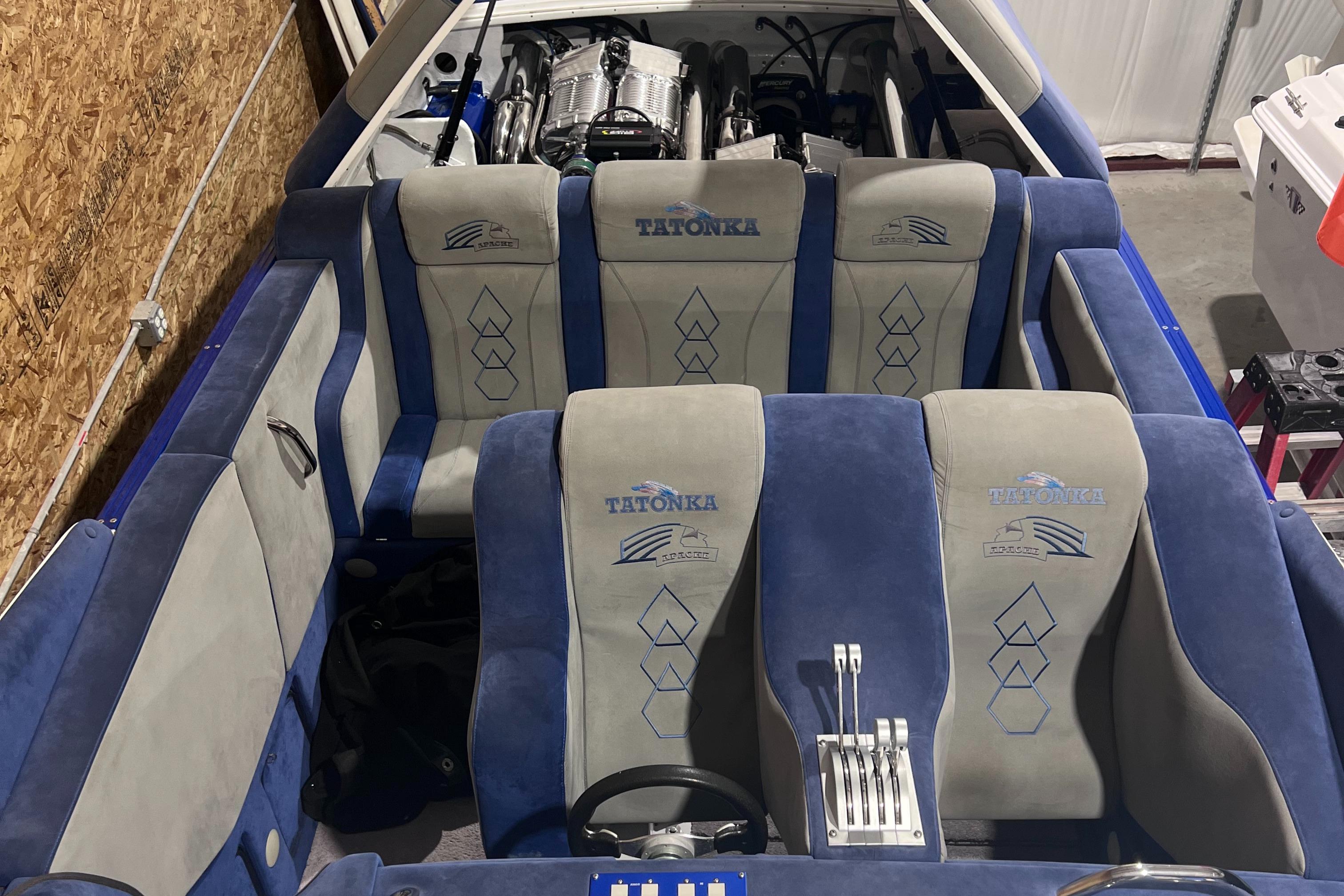 1994 Apache 41 boat interior with blue and gray seats and visible engine.
